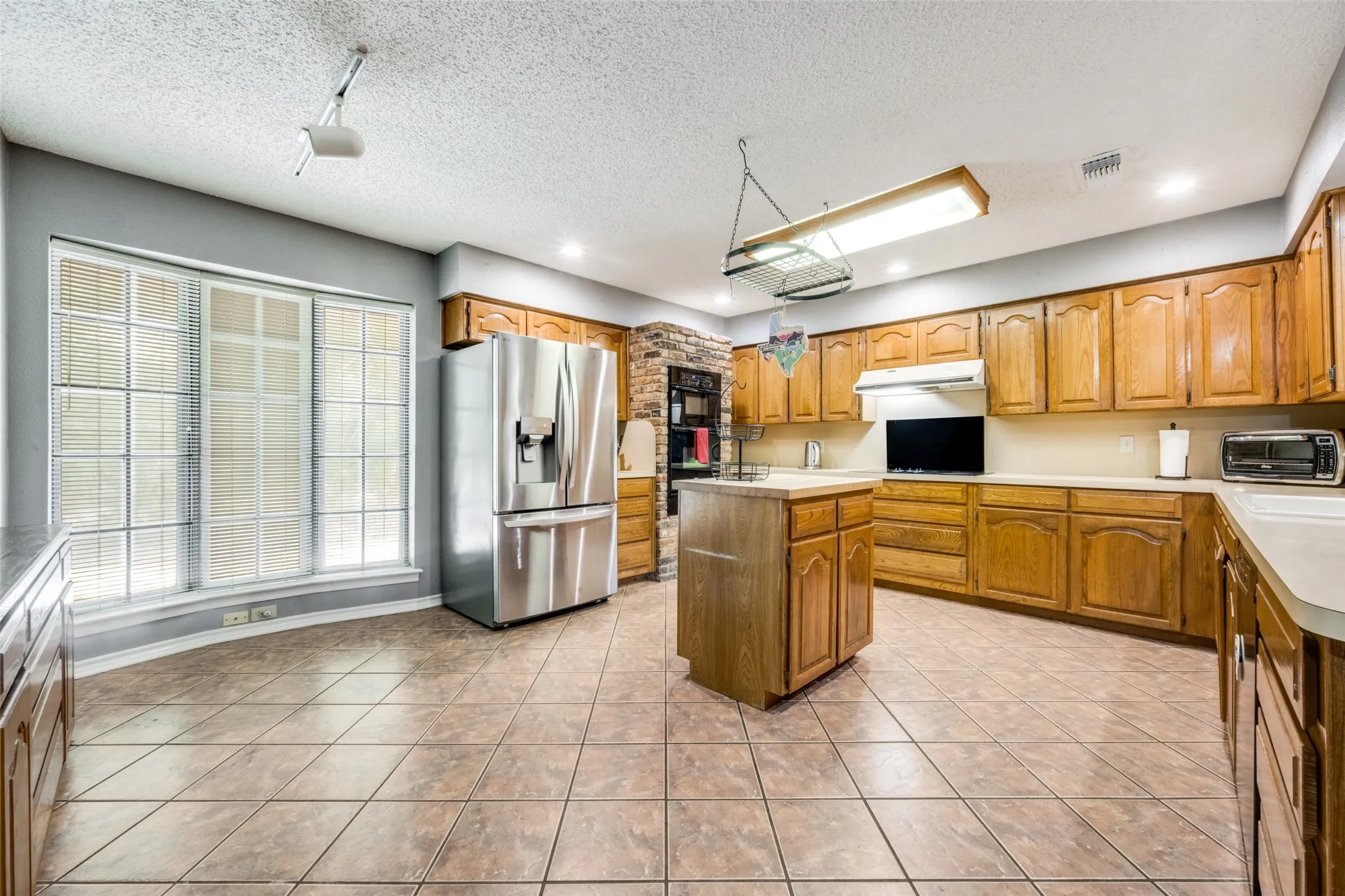 Kitchen featuring wood cabinetry, a center island, and tile flooring