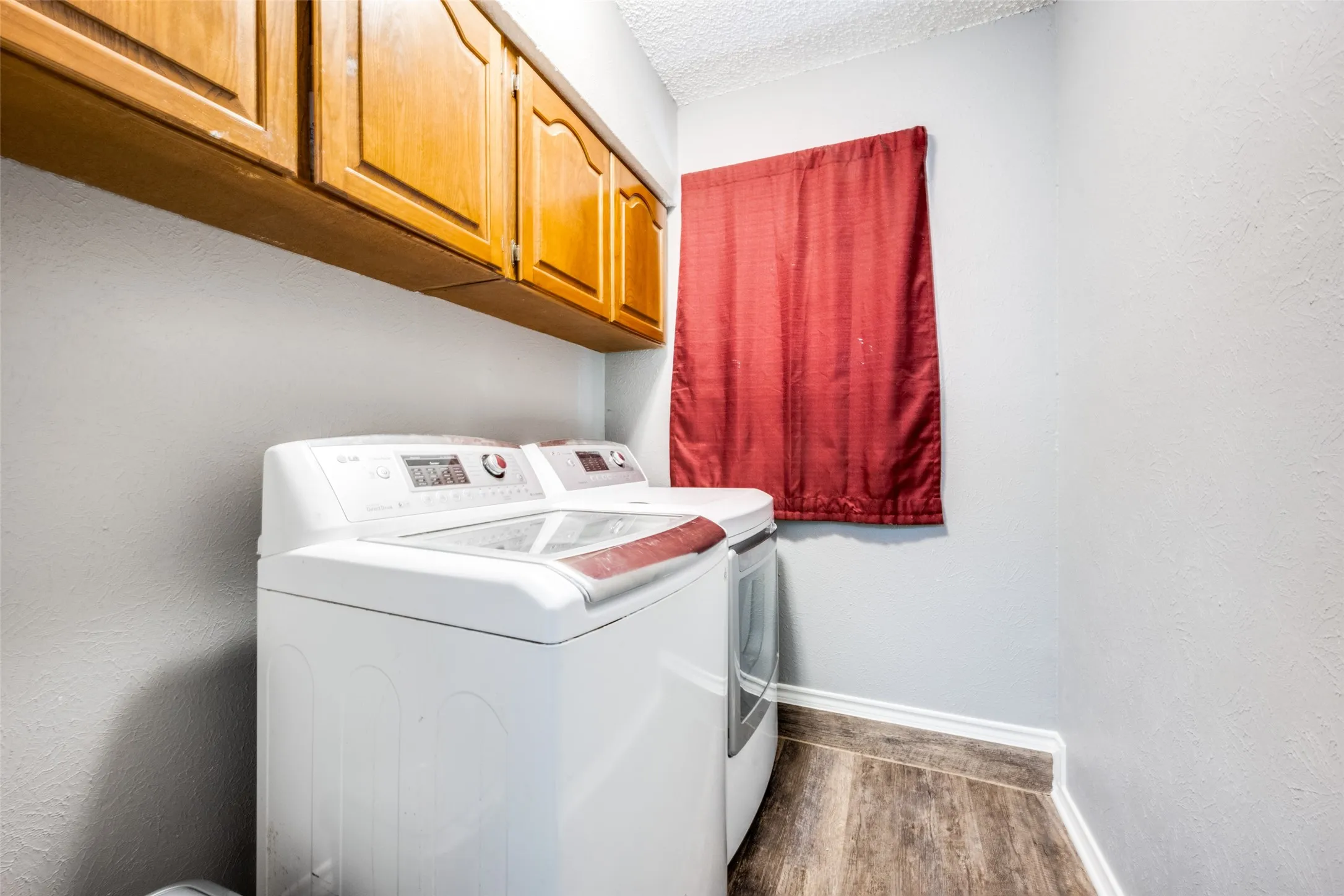 Laundry area featuring wood-finish flooring, light gray walls, and white baseboards