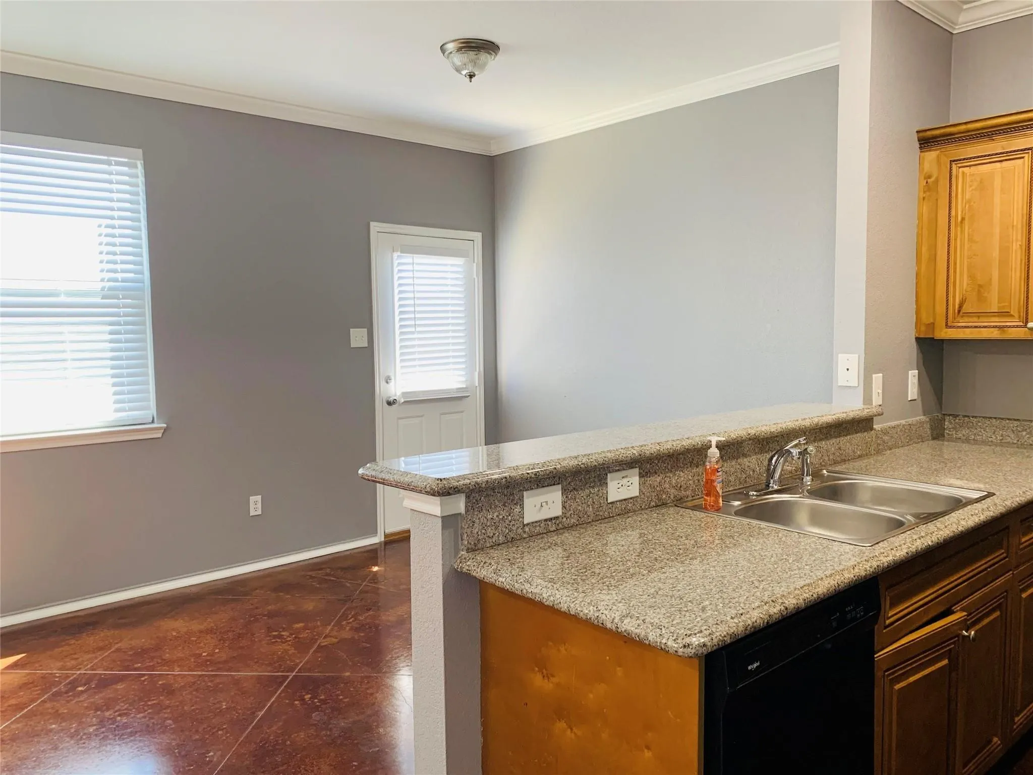 Kitchen with black dishwasher, sink, dark tile flooring, and crown molding