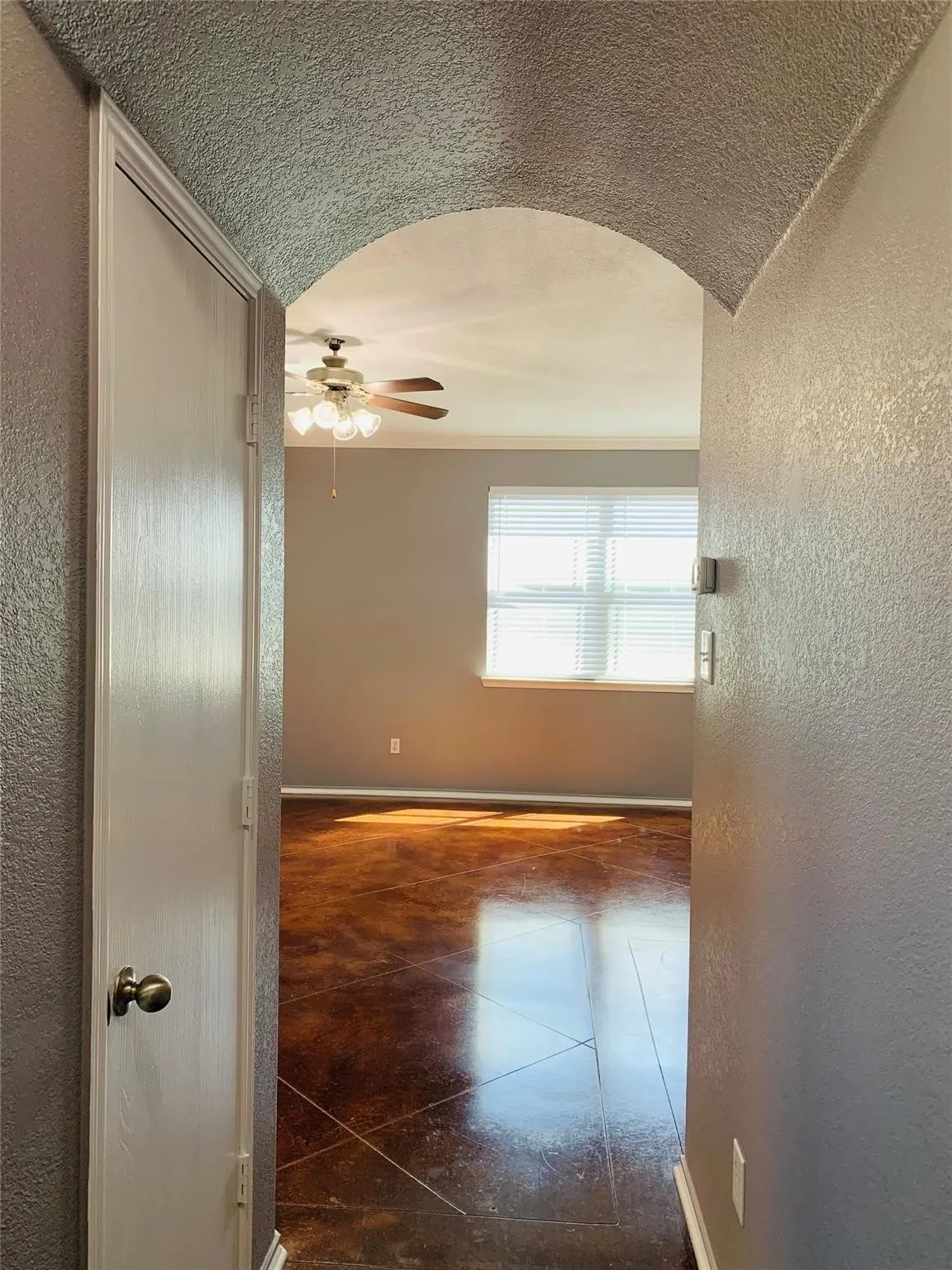 Hall with dark tile flooring, vaulted ceiling, and a textured ceiling
