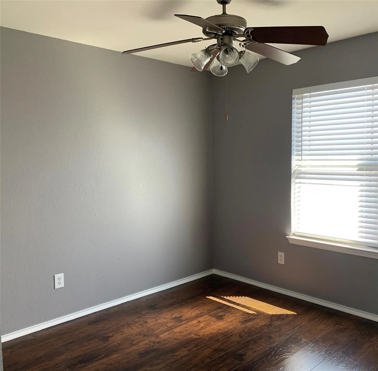 Spare room featuring a healthy amount of sunlight, hardwood / wood-style floors, and ceiling fan