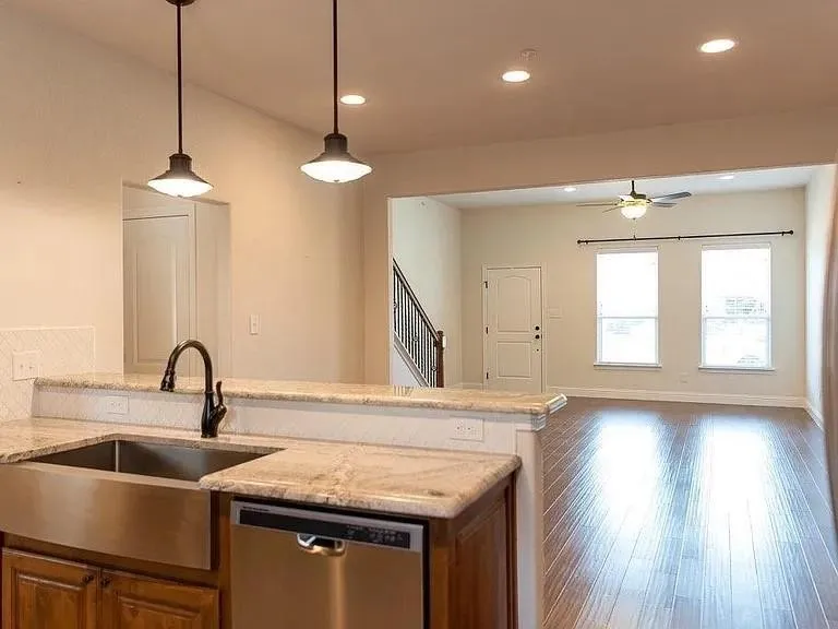 Kitchen island with a farmhouse sink, granite countertops, and a tile backsplash