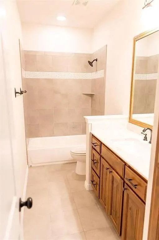 Bathroom featuring a tiled shower with a built-in niche, a white tub, and a single vanity with wood-finish cabinetry