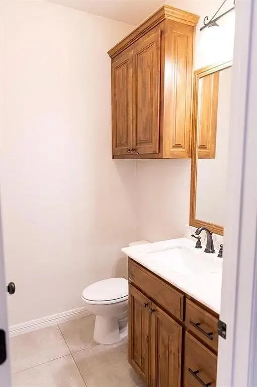 Bathroom featuring a wood-finish vanity with a white countertop and integrated sink, a dark bronze faucet, and an overhead wood-finish cabinet