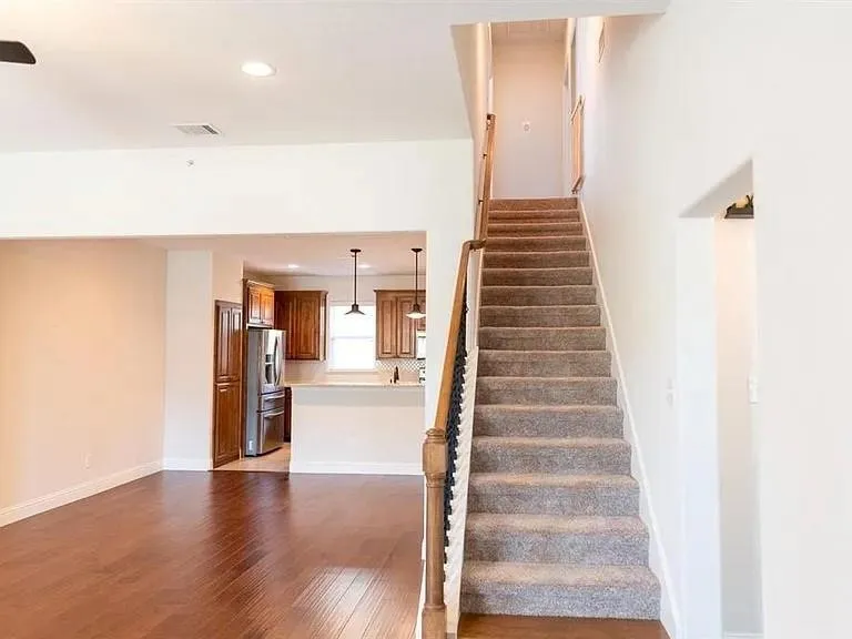 Carpeted staircase with wood handrail and black balusters