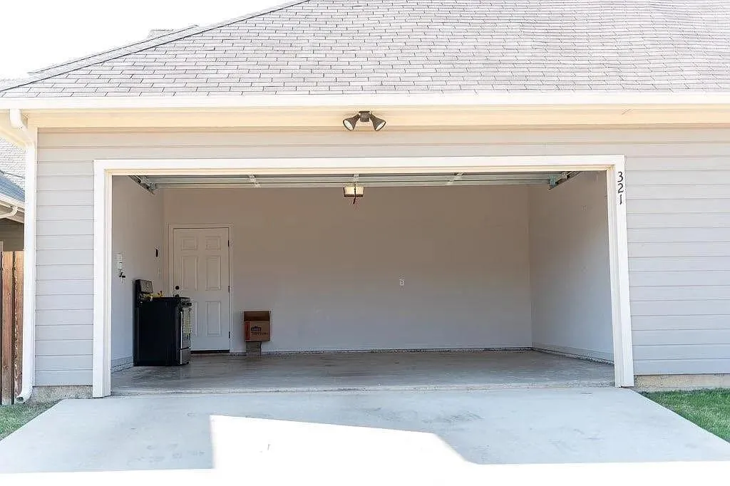 Attached two-car garage featuring a concrete floor and a white paneled door for interior access