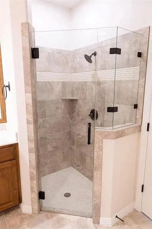 Glass-enclosed shower featuring large format tile walls, a mosaic accent band, and a built-in shower niche