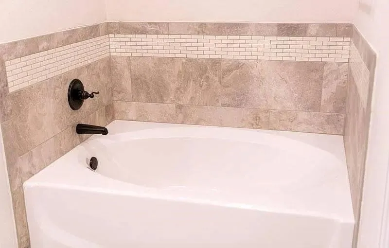White drop-in bathtub with dark bronze fixtures