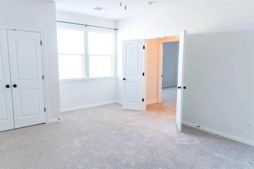Bright room featuring light-toned carpeting, two windows with blinds, and white walls