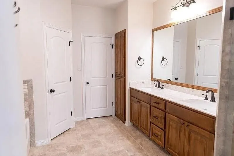 Double vanity featuring wood cabinetry, white countertops, and dual sinks with dark fixtures