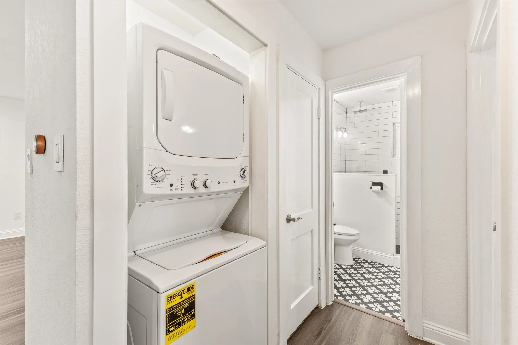 Stacked white washer and dryer unit, featuring top-loading dryer and front-loading washer