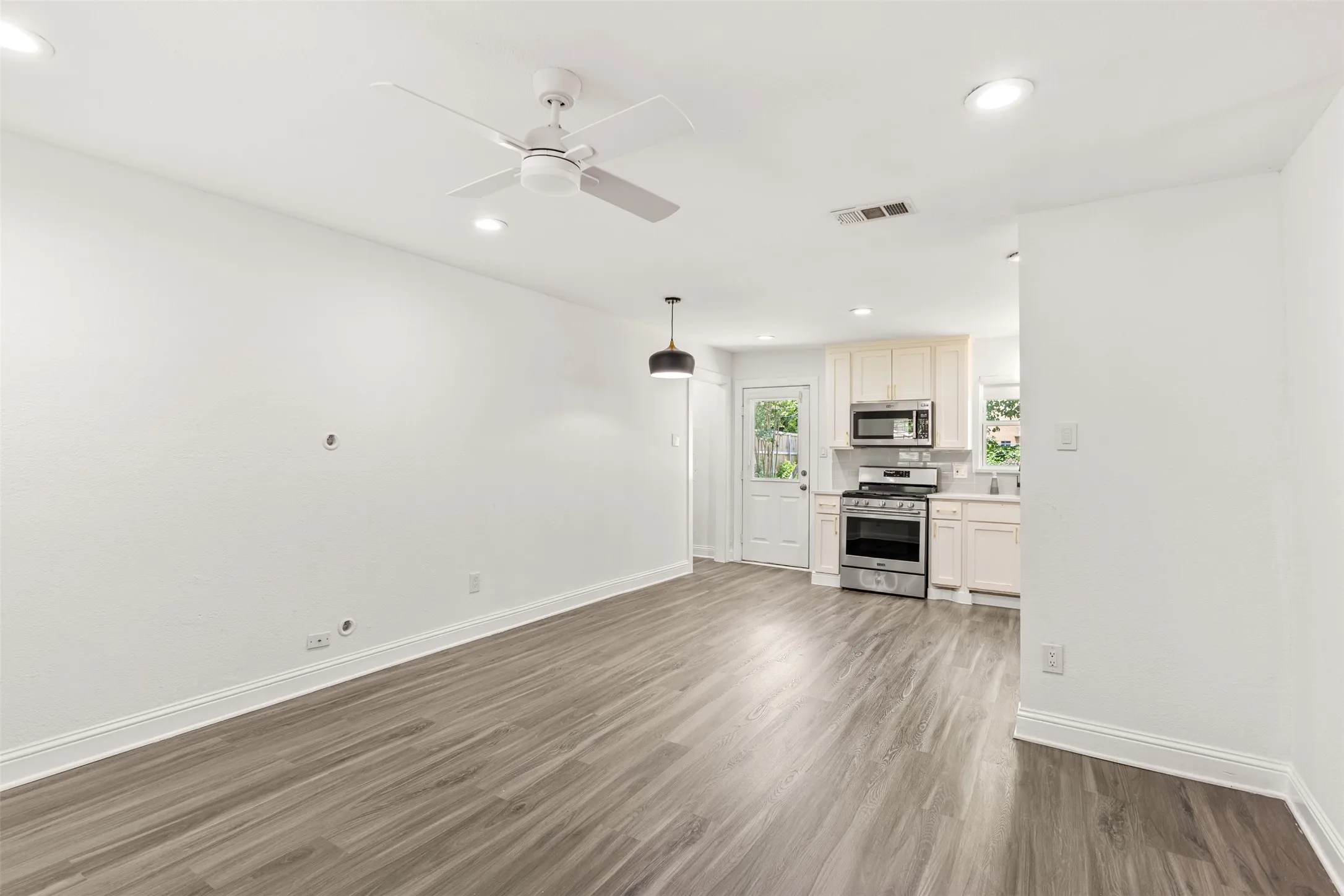 Open-concept living area featuring wood-finish flooring, recessed lighting, and a ceiling fan