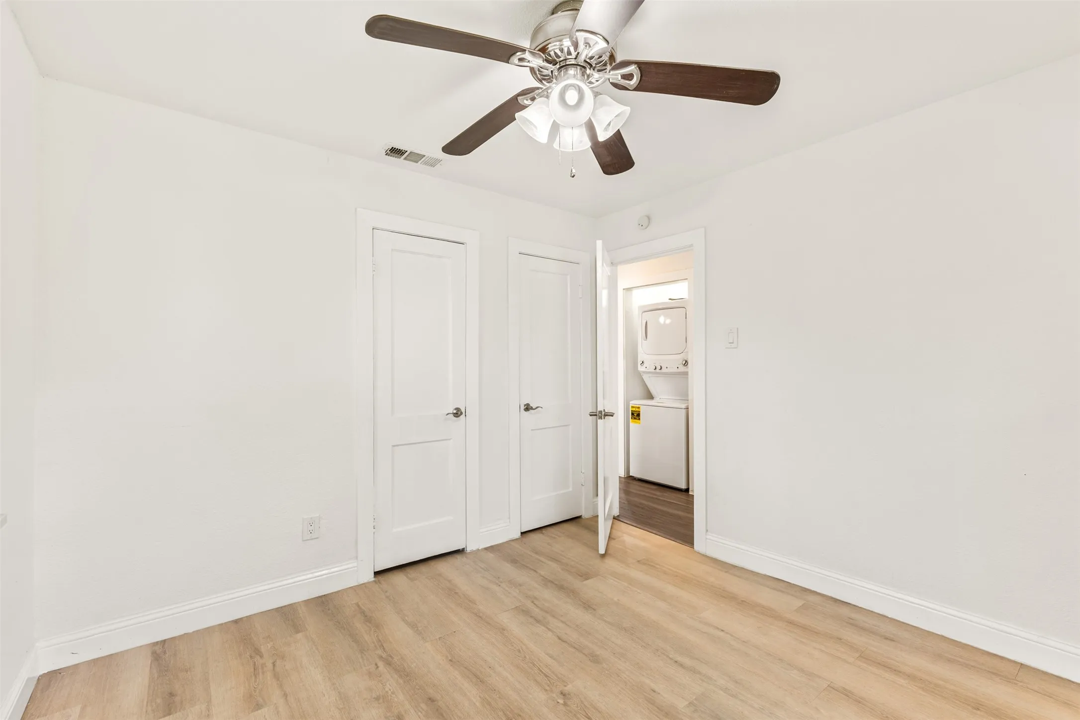 Room with wood-finish flooring, white walls, and white baseboards