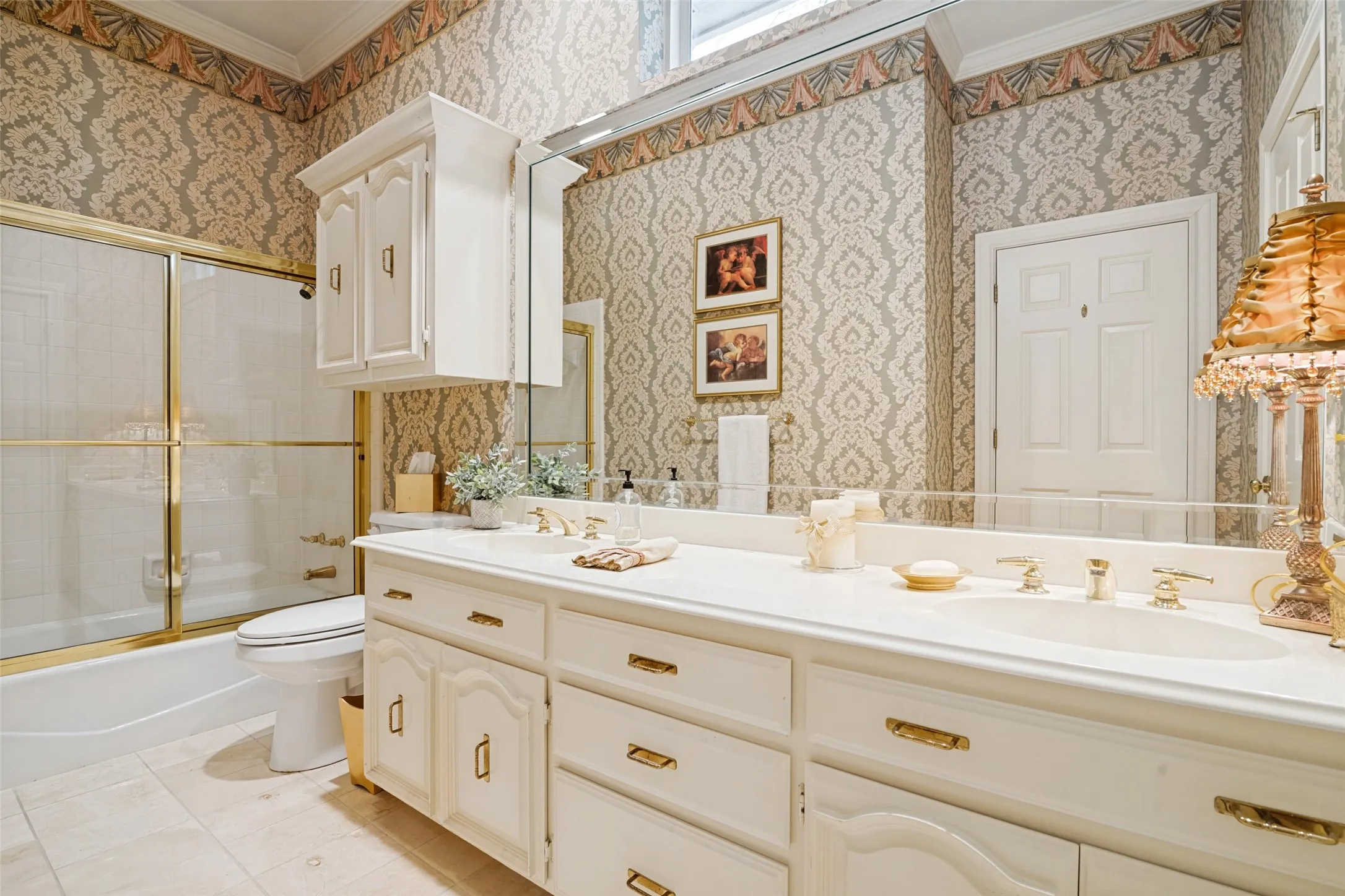 Bathroom featuring a dual vanity with integrated sinks, gold-tone hardware, and a framed mirror
