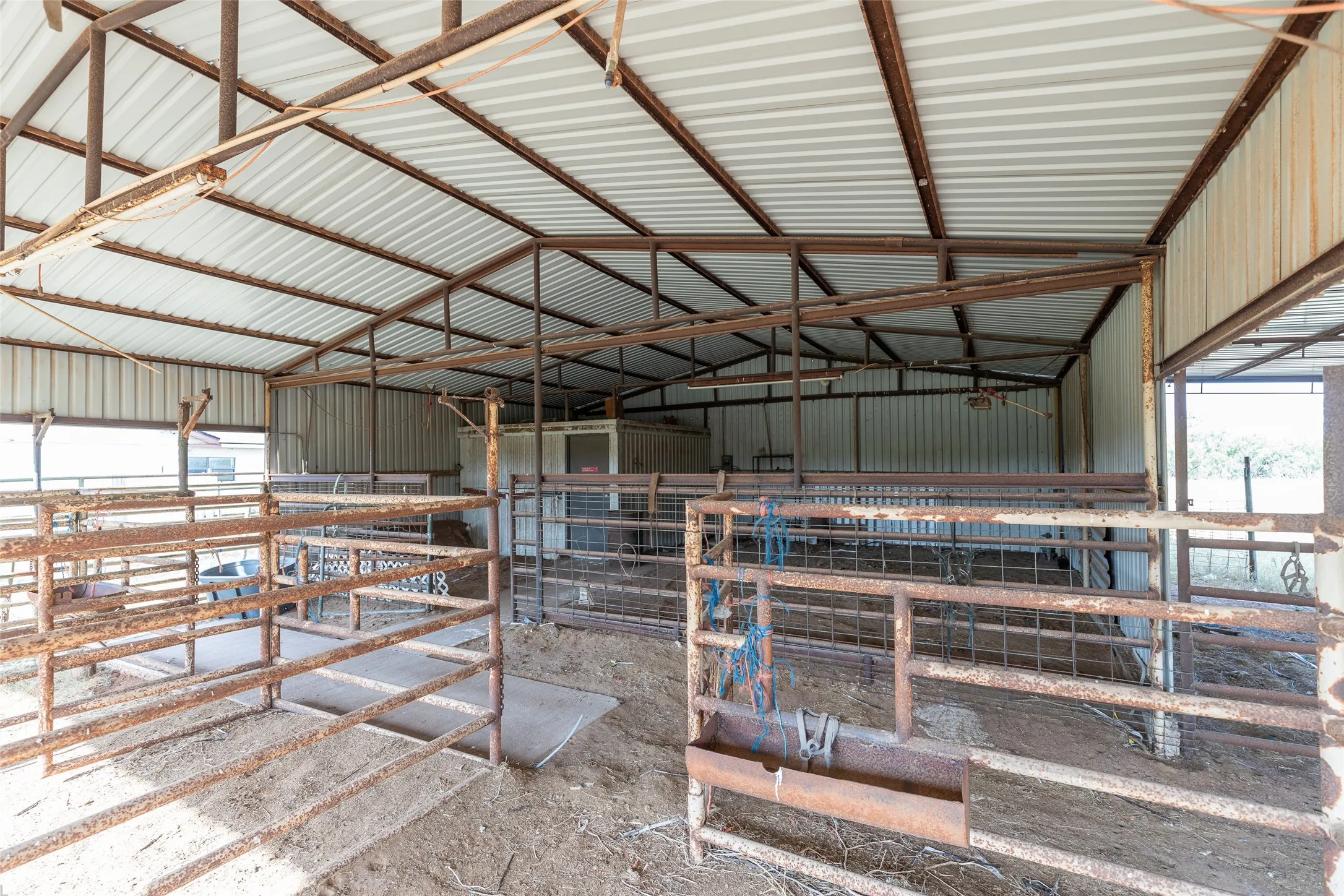 Open-sided barn structure featuring a corrugated metal roof and metal framing