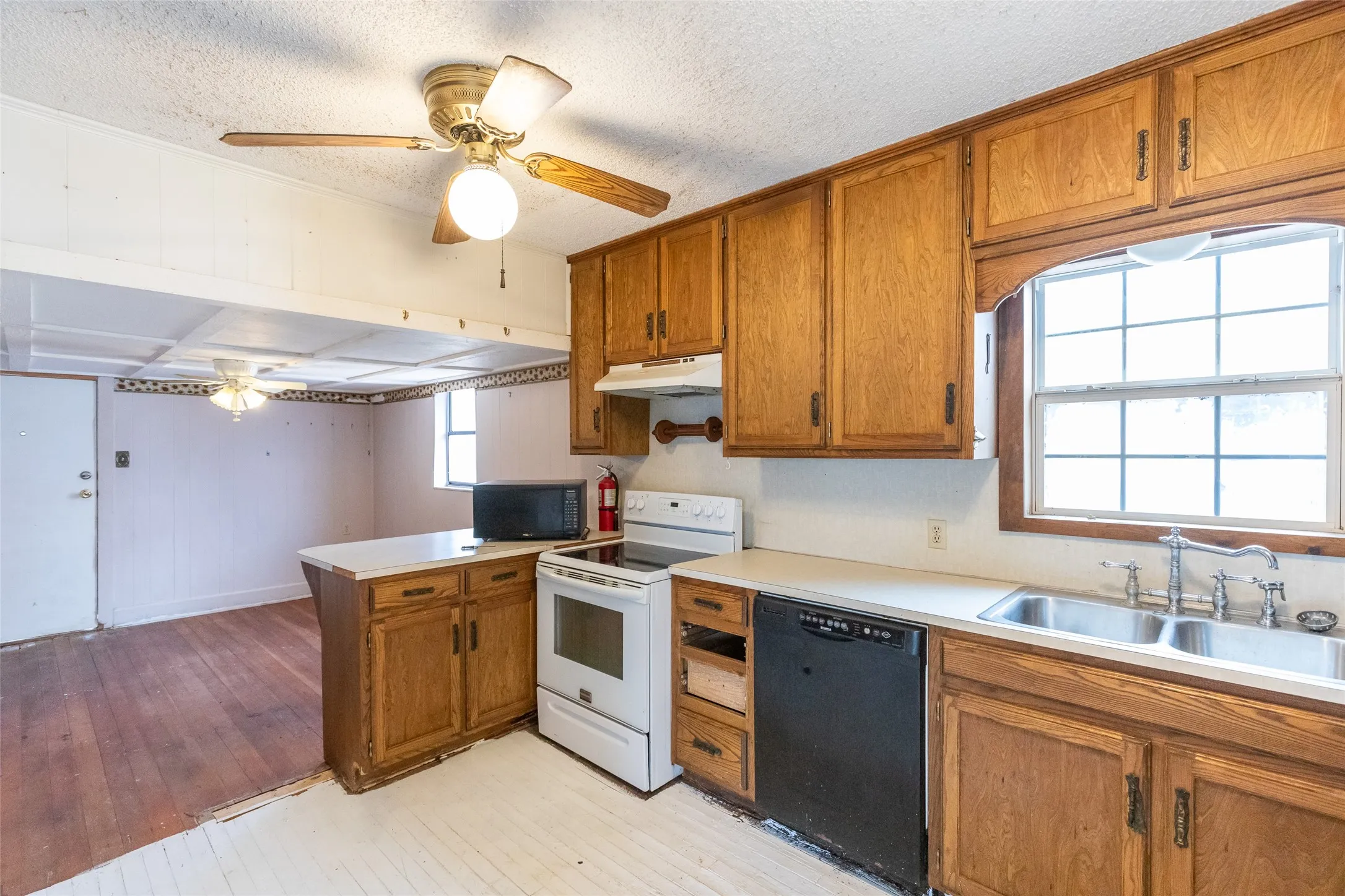 Kitchen featuring wood cabinetry, white countertops, dual basin stainless steel sink, and a built-in dishwasher