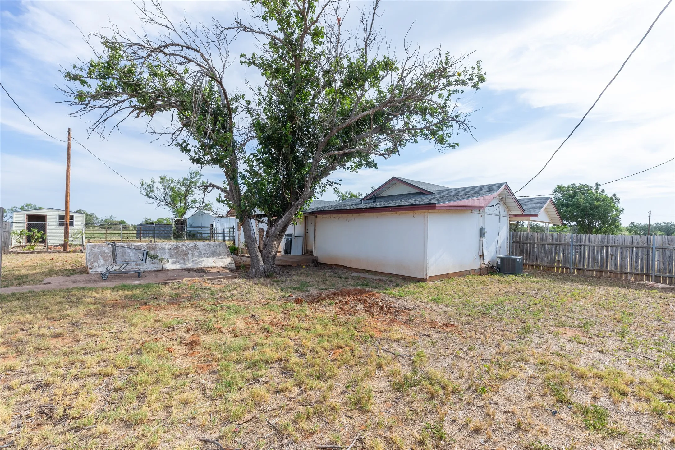 Expansive yard featuring a mature tree, a wooden privacy fence, and an air conditioning unit