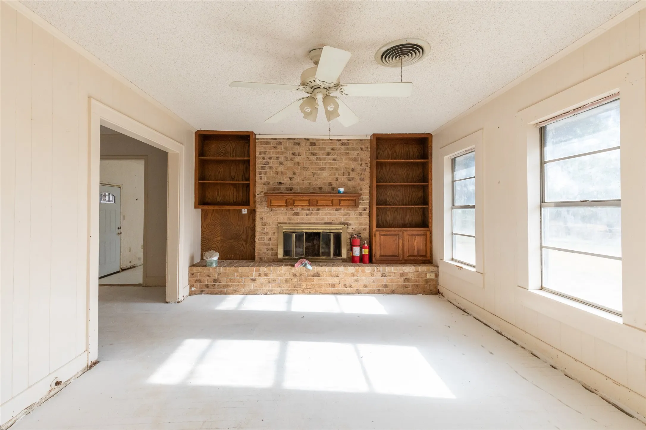Brick fireplace with a wood mantle and built-in shelving units