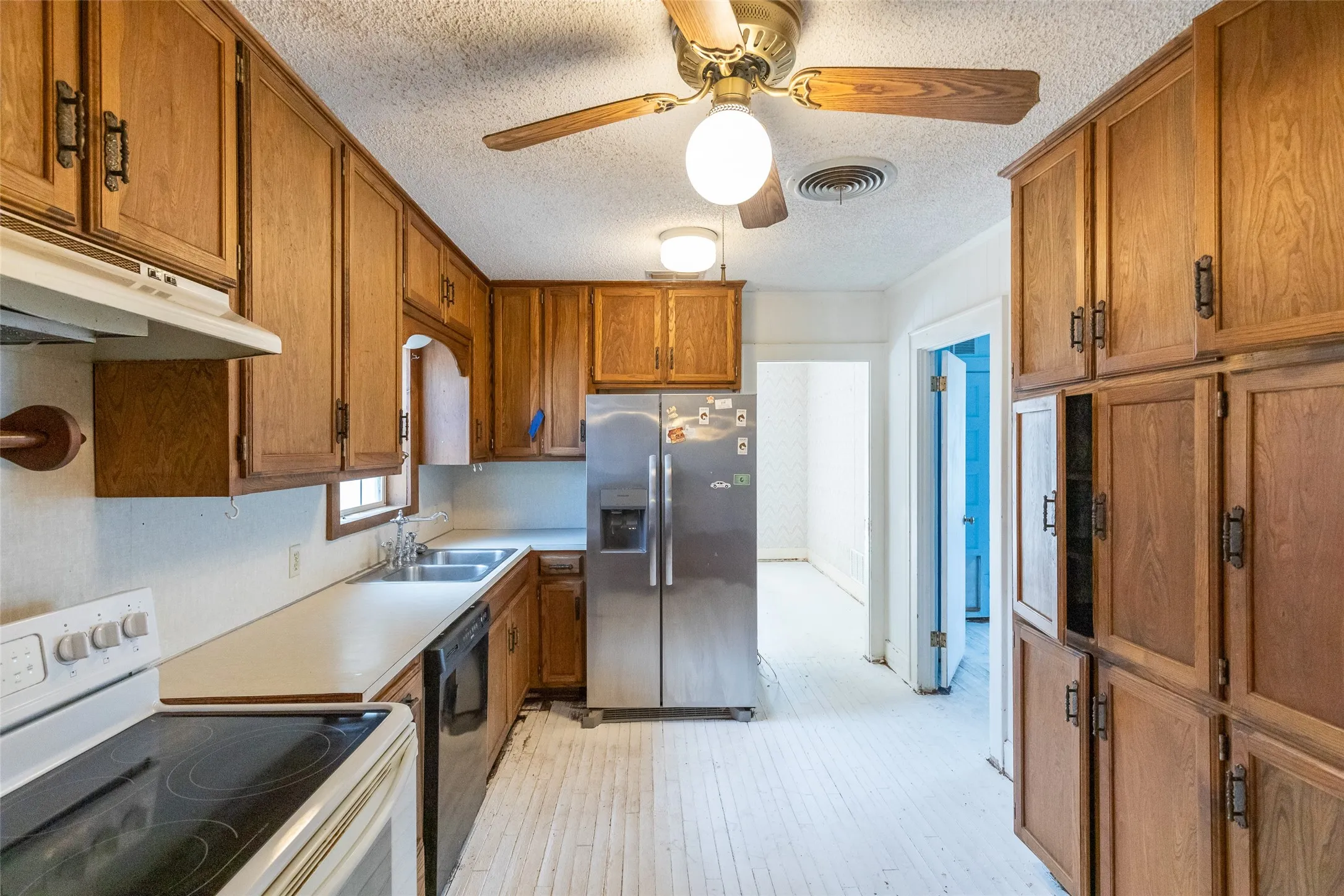Kitchen featuring extensive wood cabinetry, white countertops, a double basin sink, and a stainless steel refrigerator