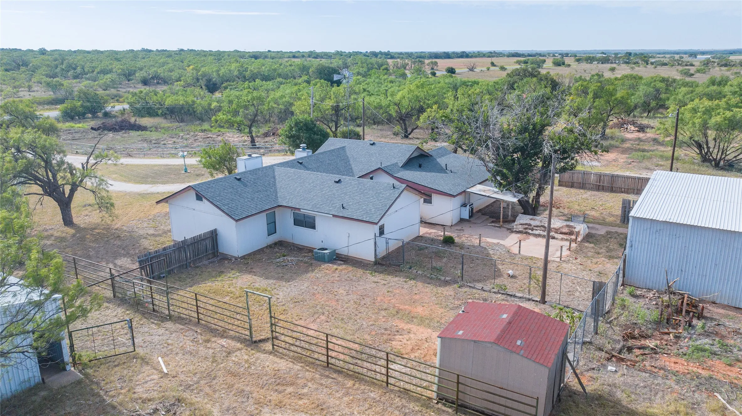 Ranch-style residence featuring a grey shingle roof, white exterior siding, and multiple fenced areas