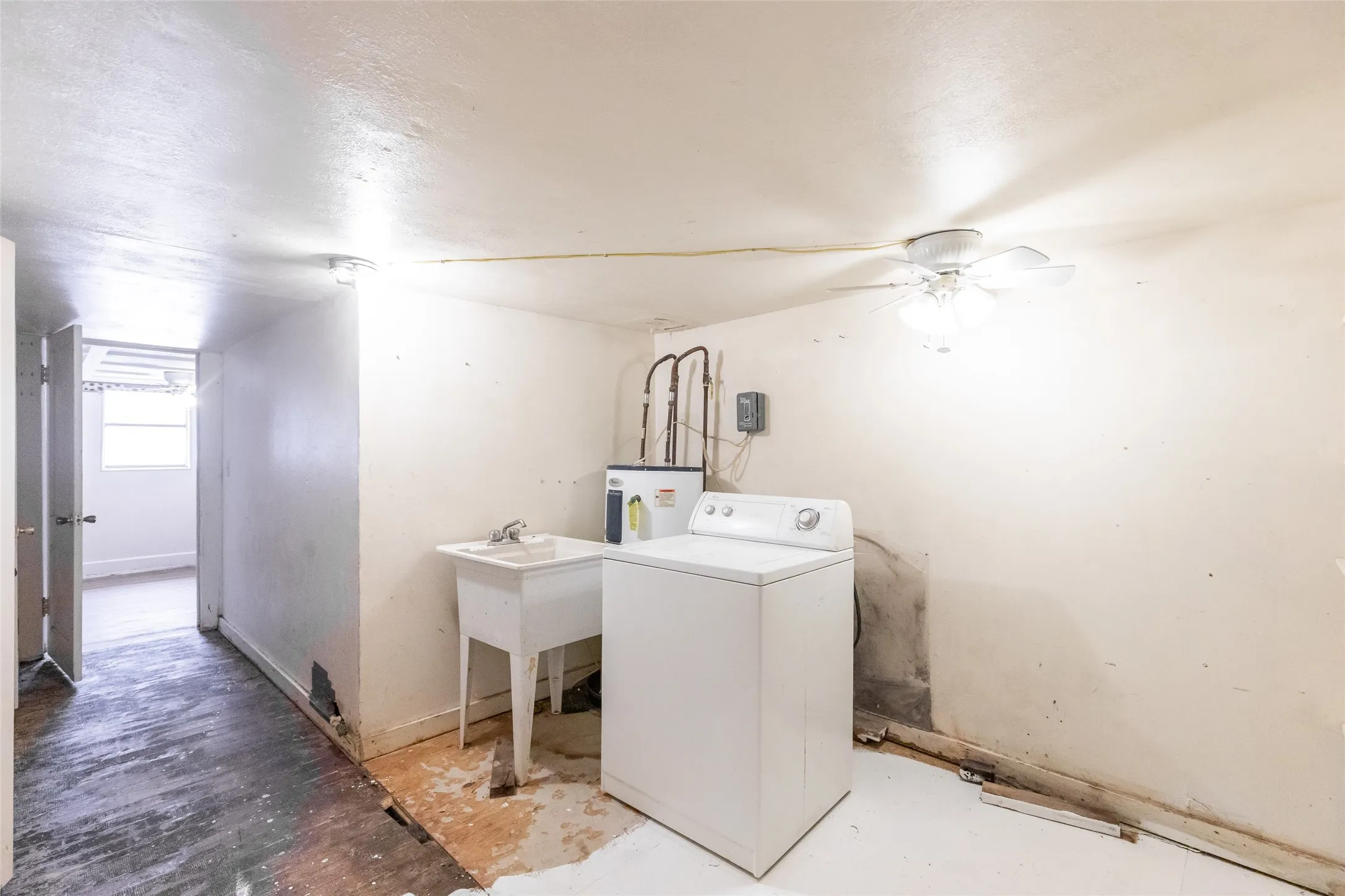 Utility area featuring a laundry sink, washing machine, and ceiling fan with light fixture