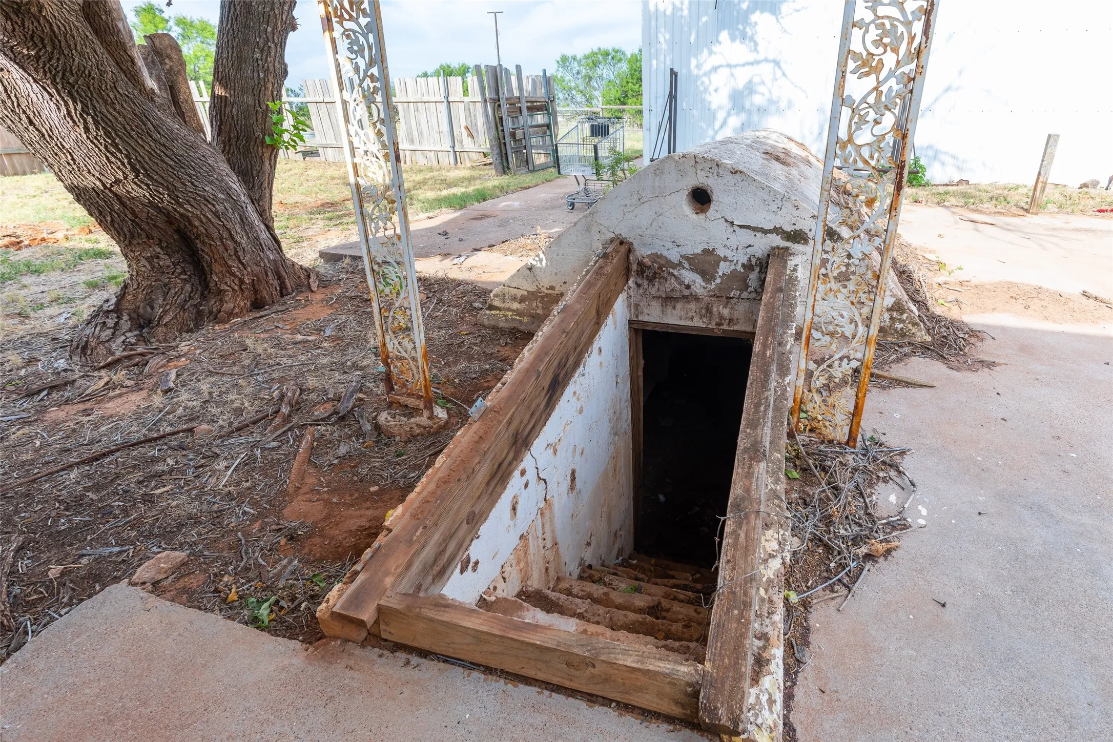 Concrete steps descend into an underground space, framed by a concrete entrance with a circular vent