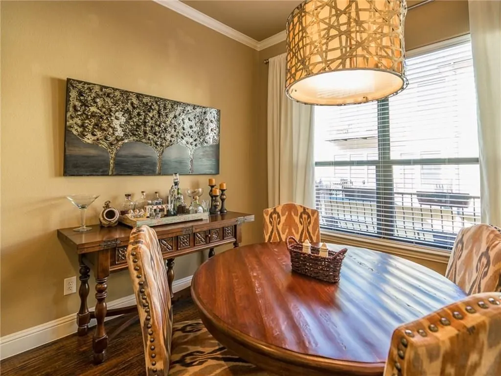 Dining area featuring wood-finish flooring, crown molding, a large window with blinds and drapes, and an overhead decorative light fixture
