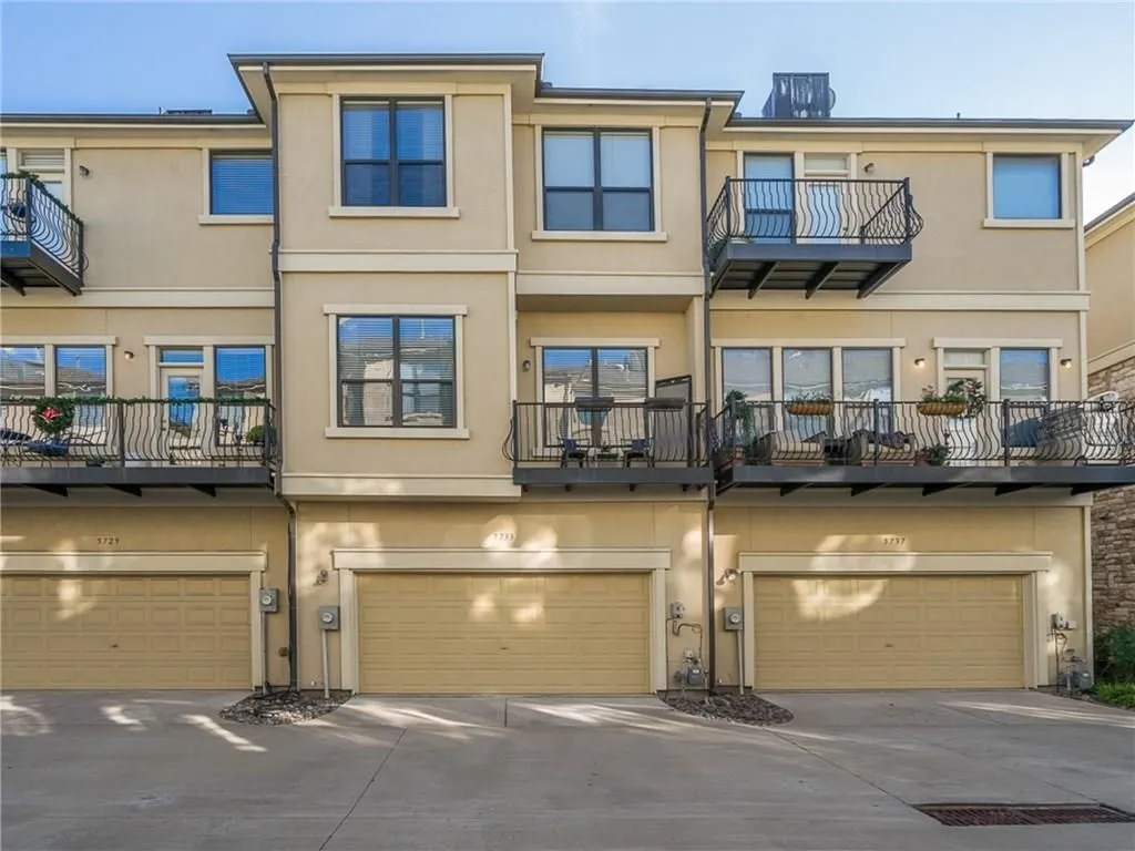 Multi-level stucco exterior with three distinct garage bays