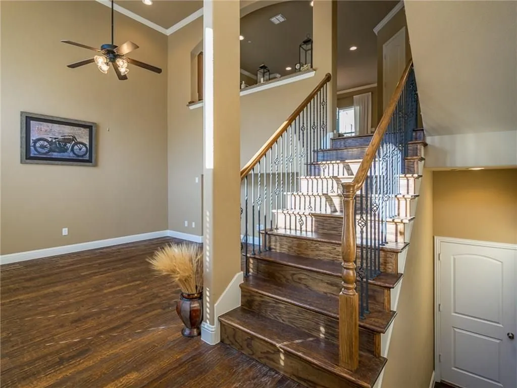 Grand staircase featuring wood treads, ornate wrought iron balusters, and a rich wood handrail