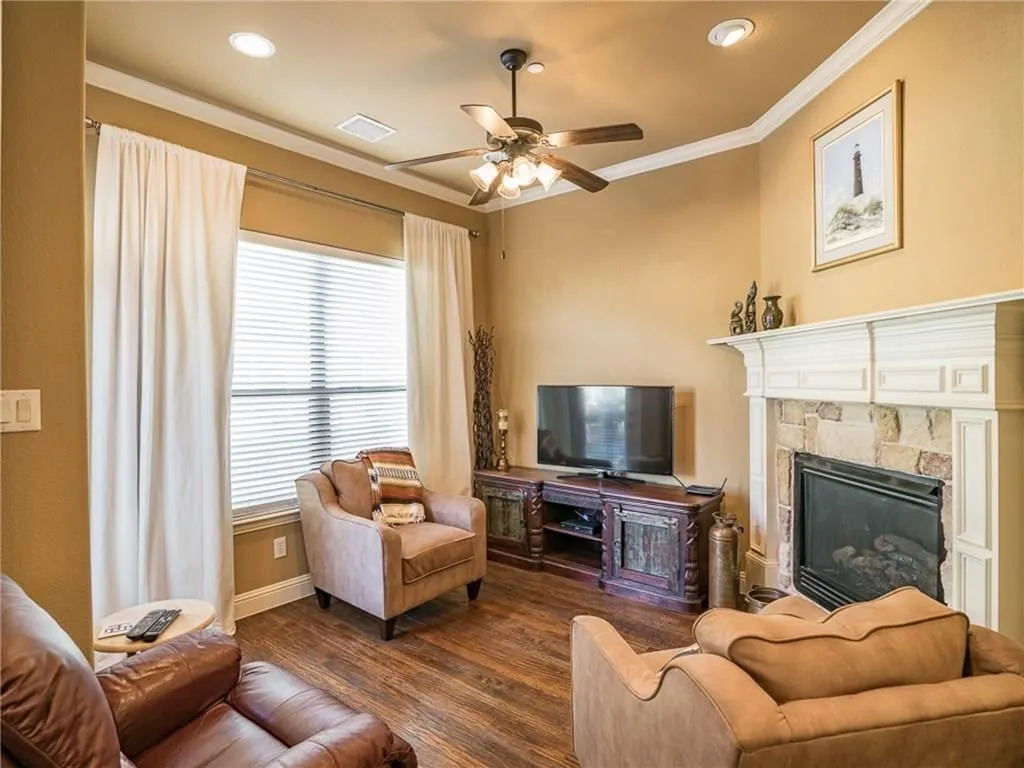 Living area featuring a stone fireplace with a white mantel, wood-finish flooring, and recessed lighting
