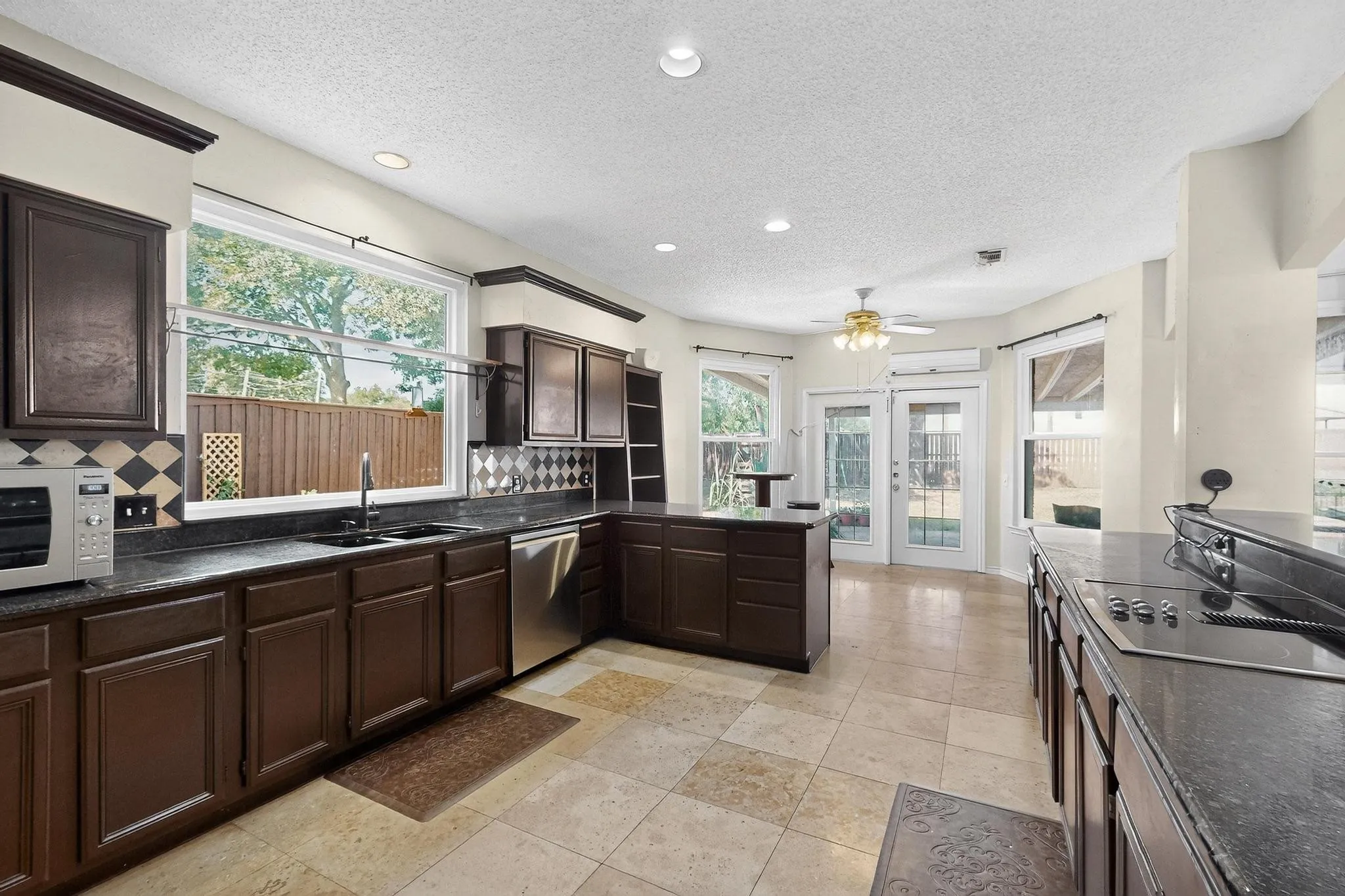 Spacious kitchen featuring dark wood cabinetry, solid surface countertops, and tile flooring