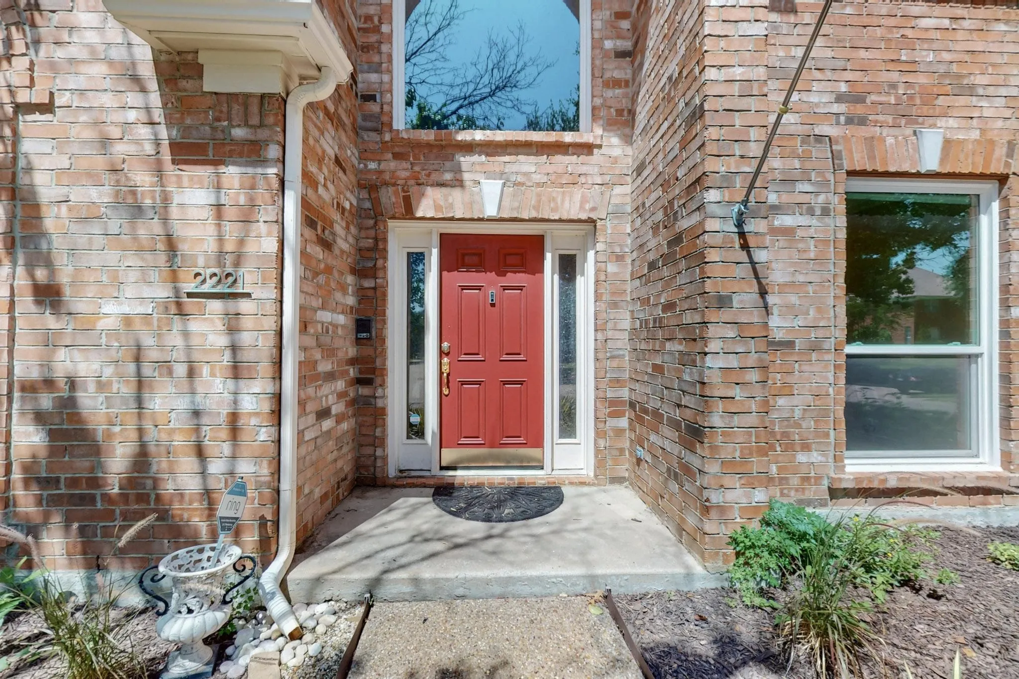 Brick exterior with a prominent red entry door, framed by white sidelights and trim