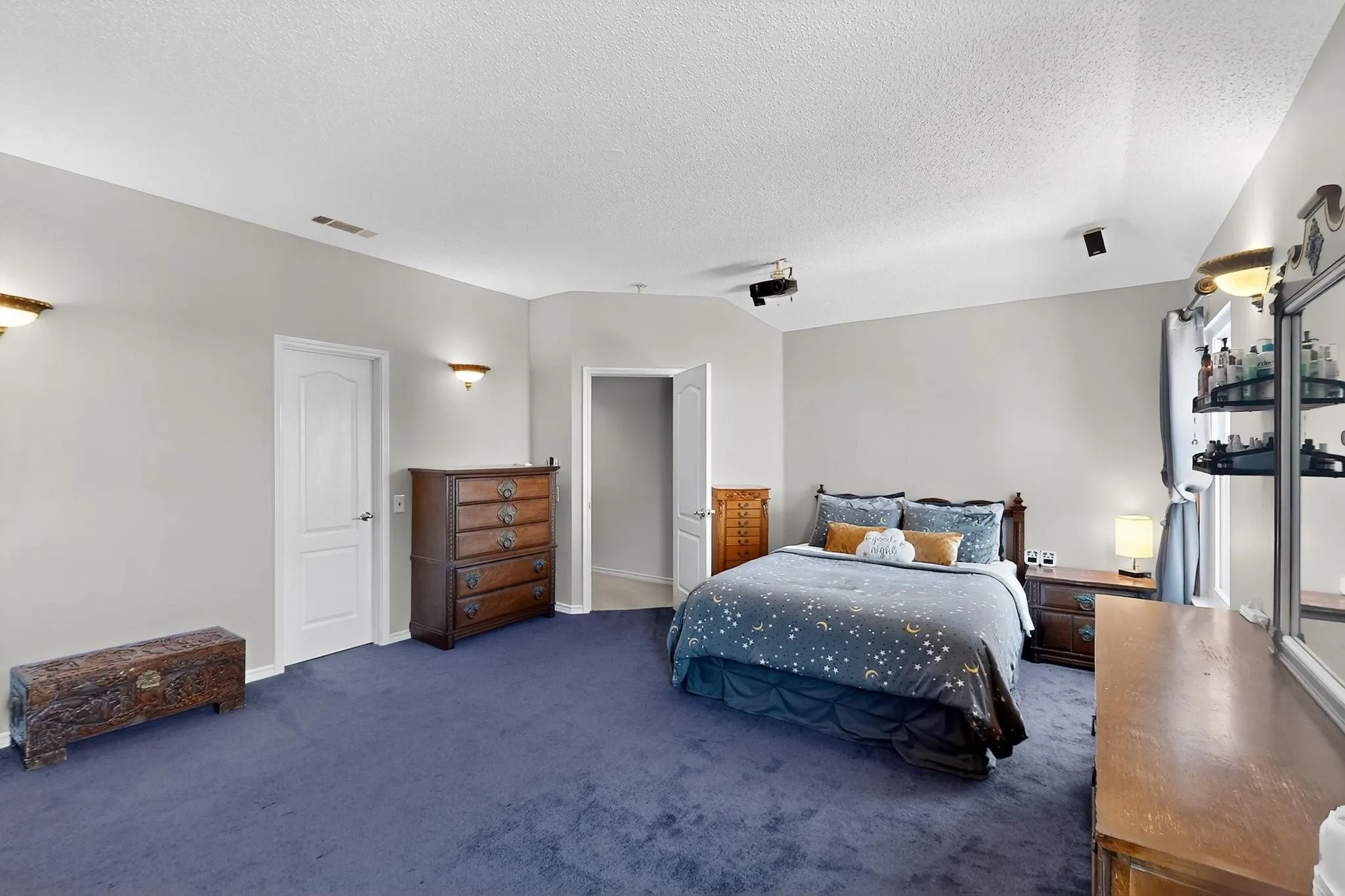 Spacious room featuring vaulted ceilings, track lighting, and a neutral wall palette