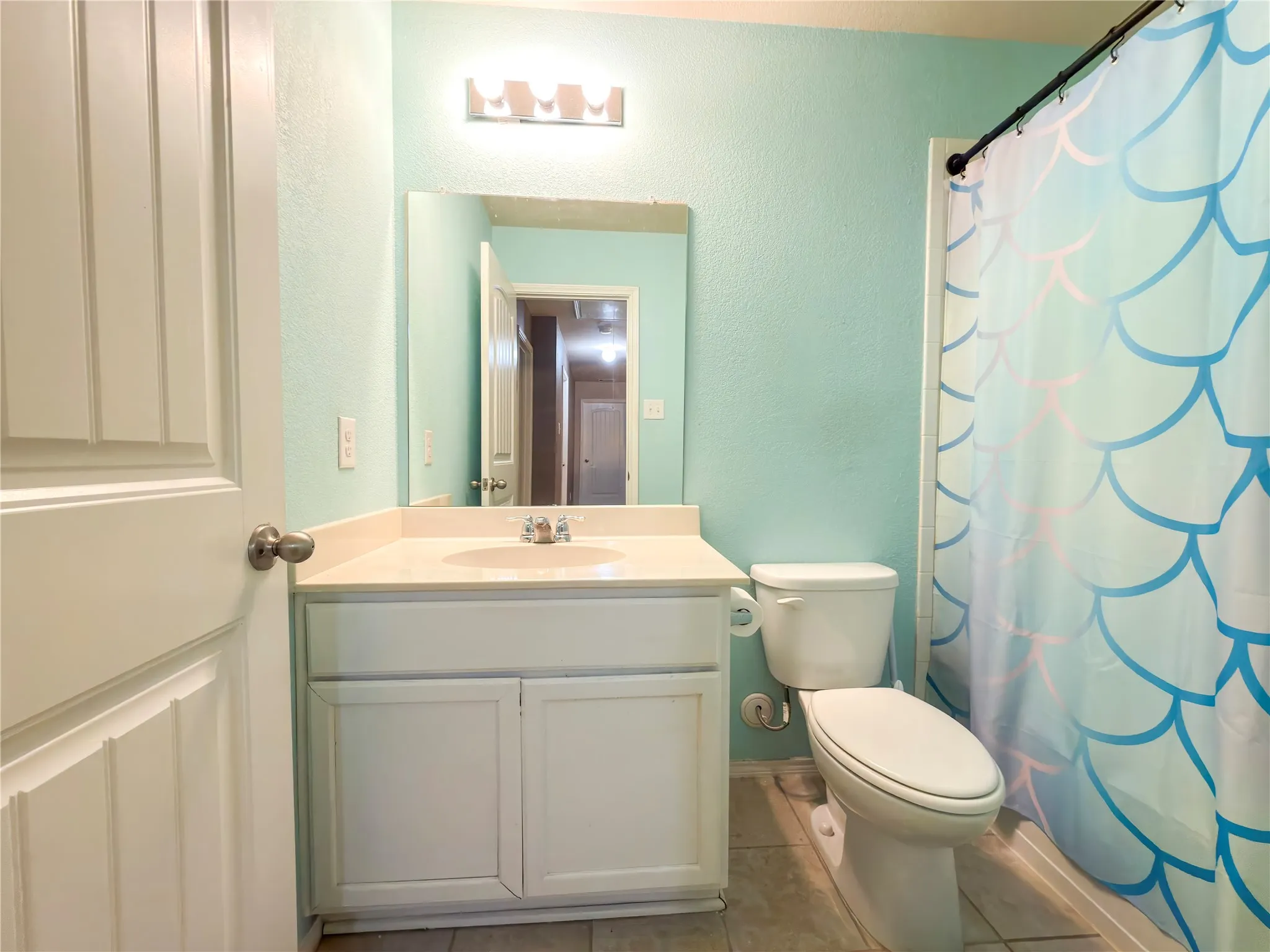 Bathroom featuring a single-basin vanity with a light-colored countertop and white cabinetry, a toilet, and tiled flooring