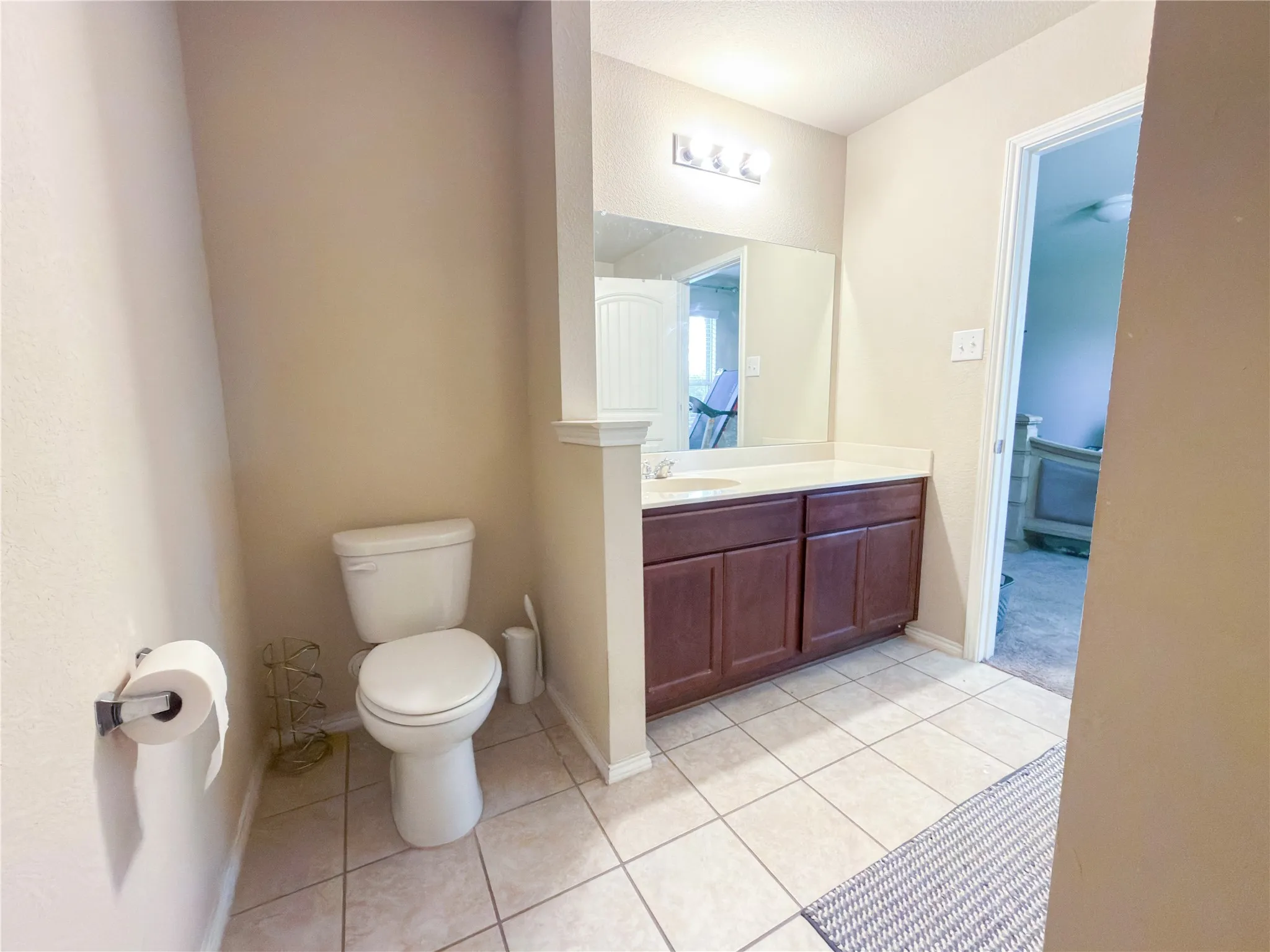 Bathroom featuring a vanity with dark wood-finish cabinetry, a white countertop, and a large mirror with a three-bulb light fixture