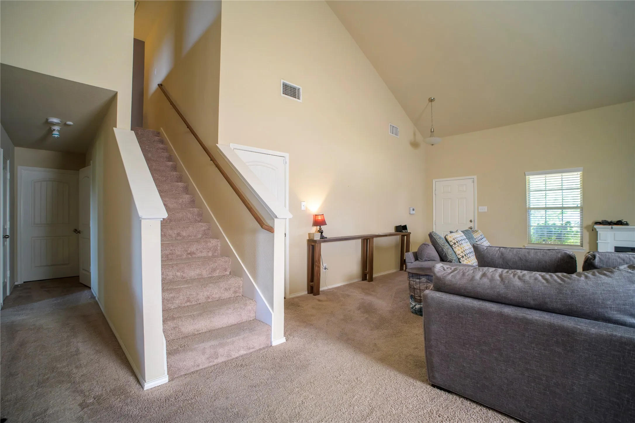 Carpeted staircase with white newel posts and wood handrail