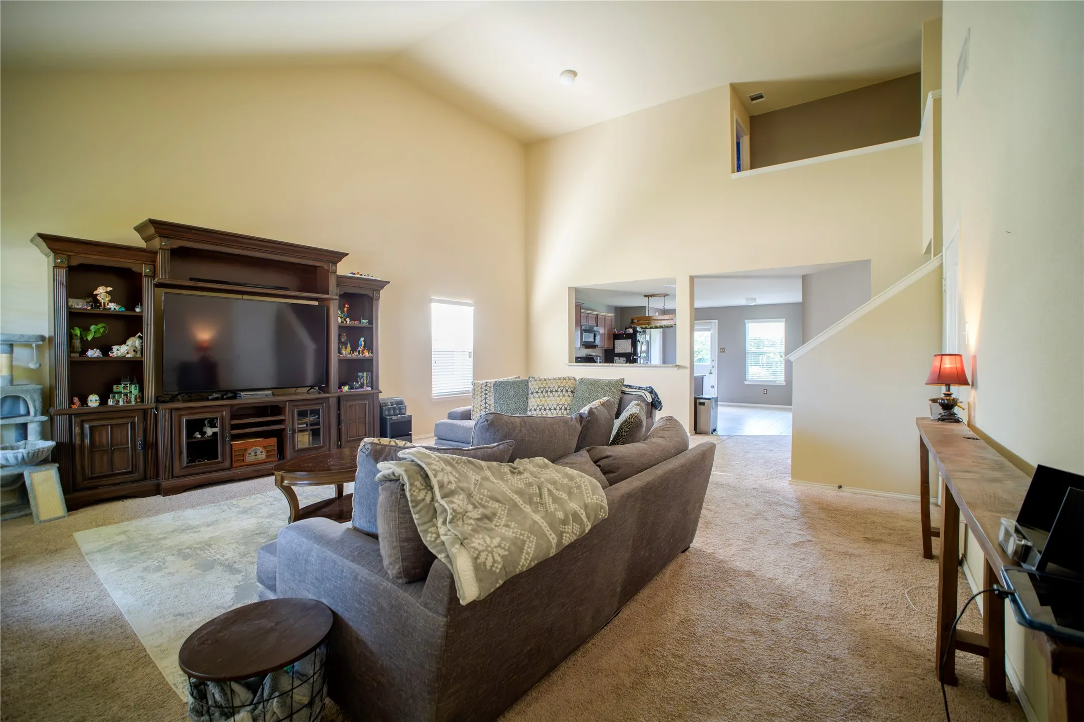 Spacious living area featuring a vaulted ceiling and neutral wall tones
