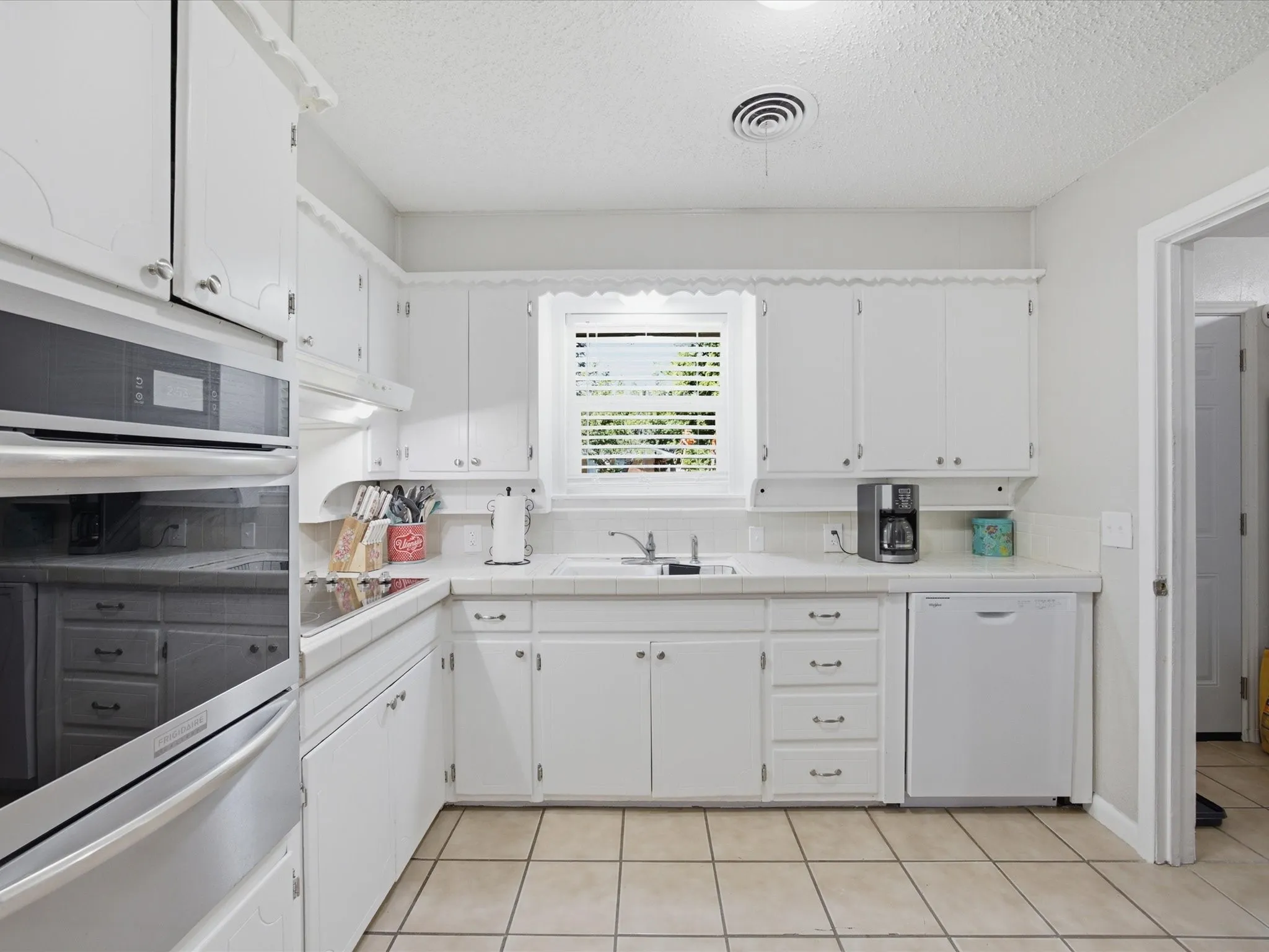 Kitchen with white cabinetry, tile countertops, and New Stainless Steel Oven Installed July 2026