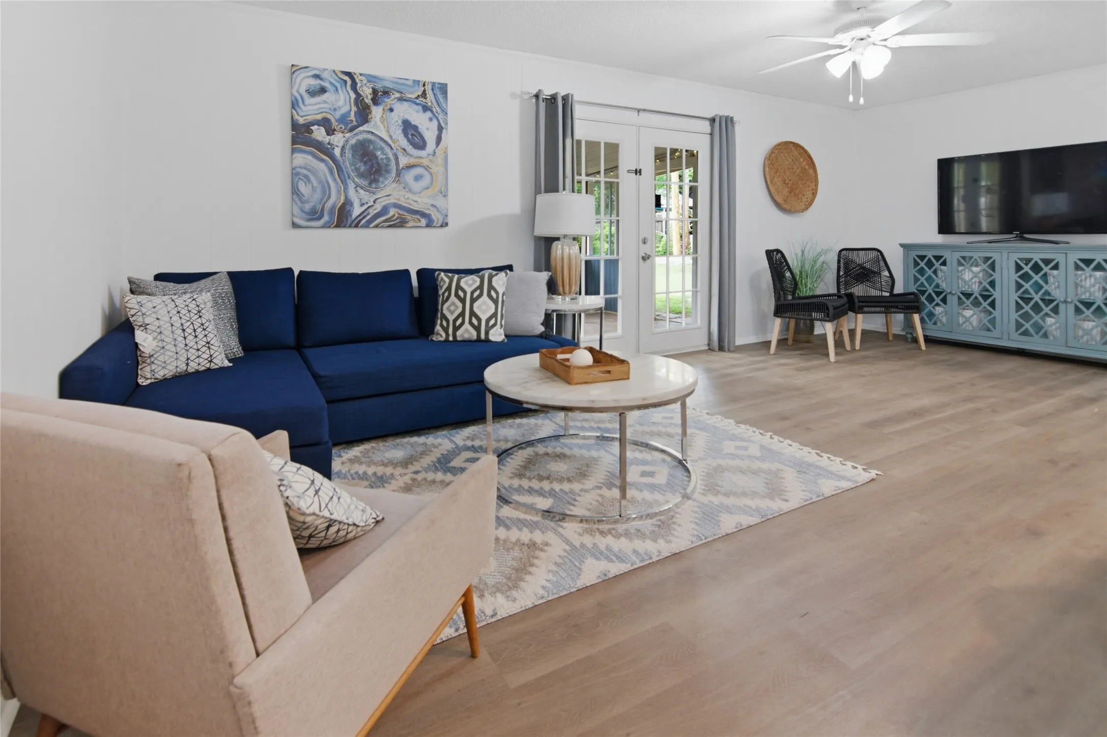 Spacious room featuring light wood-finish flooring, white walls, and a ceiling fan with integrated lighting