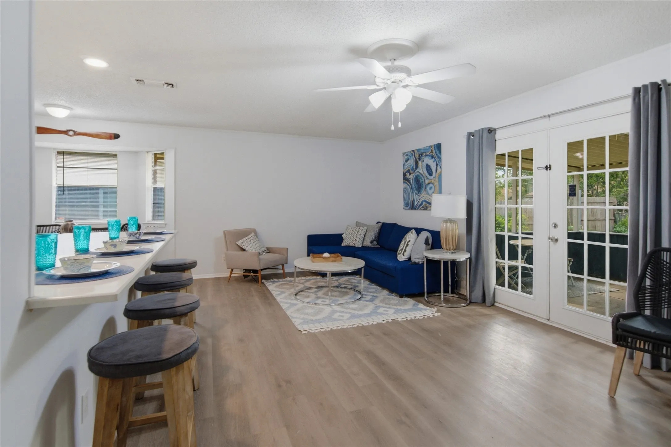 Open-concept living area with wood-finish flooring, a breakfast bar, and recessed lighting