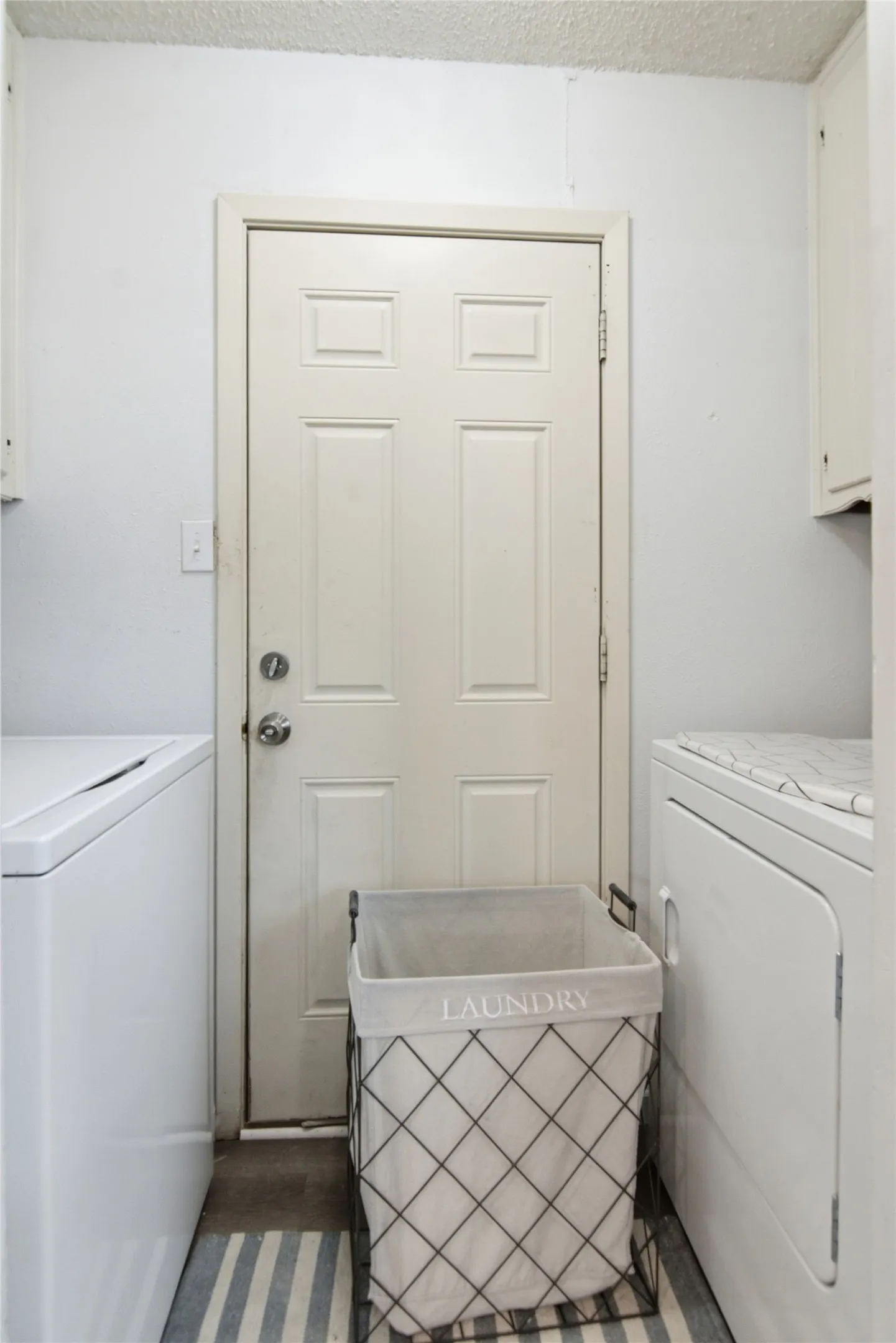 Utility area featuring a paneled door, white walls, and a textured ceiling