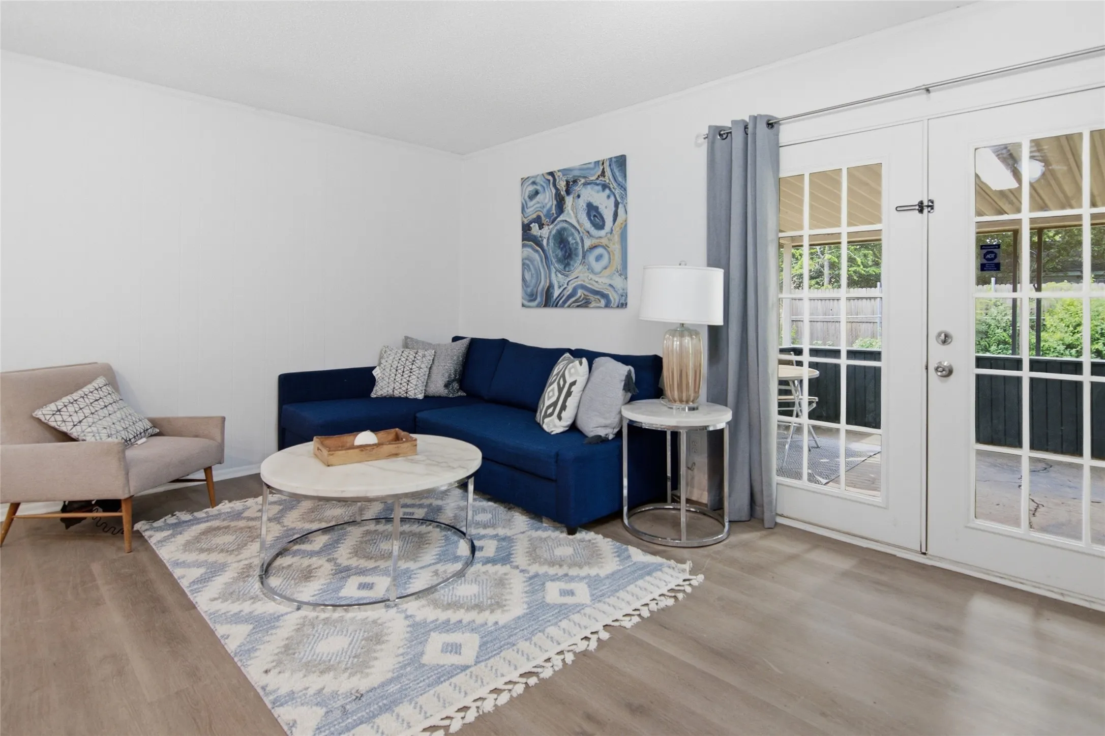 Living area featuring wood-finish flooring, white walls, and double French doors opening to an outdoor patio space