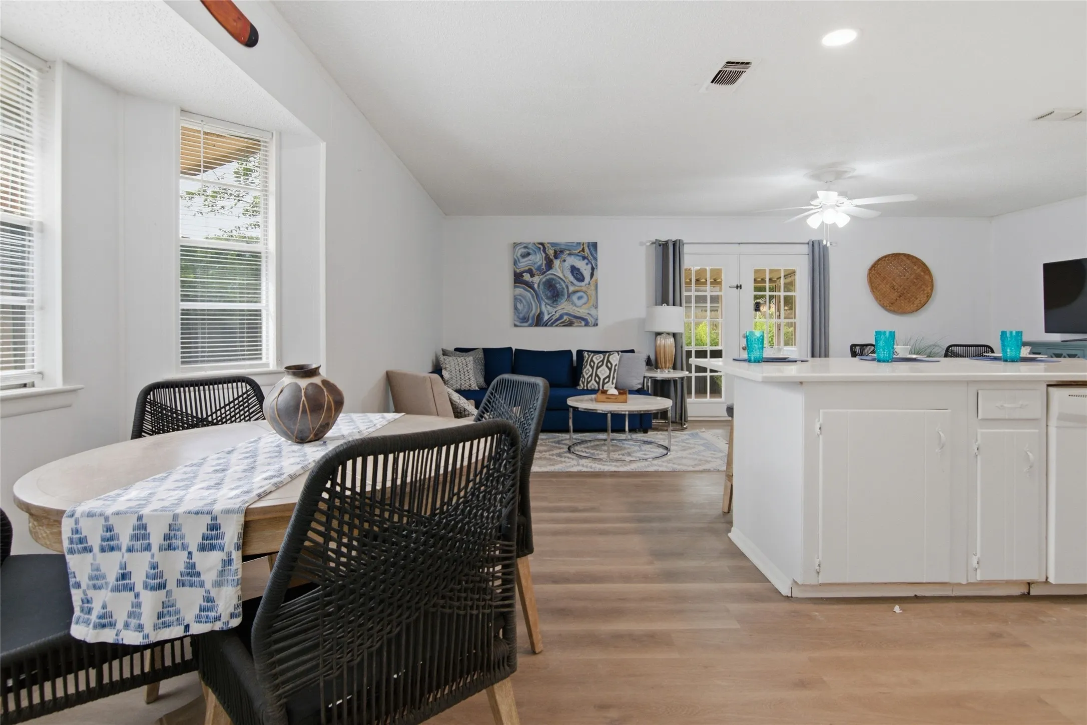 Open-concept living space featuring wood-finish flooring, white walls, and vaulted ceilings