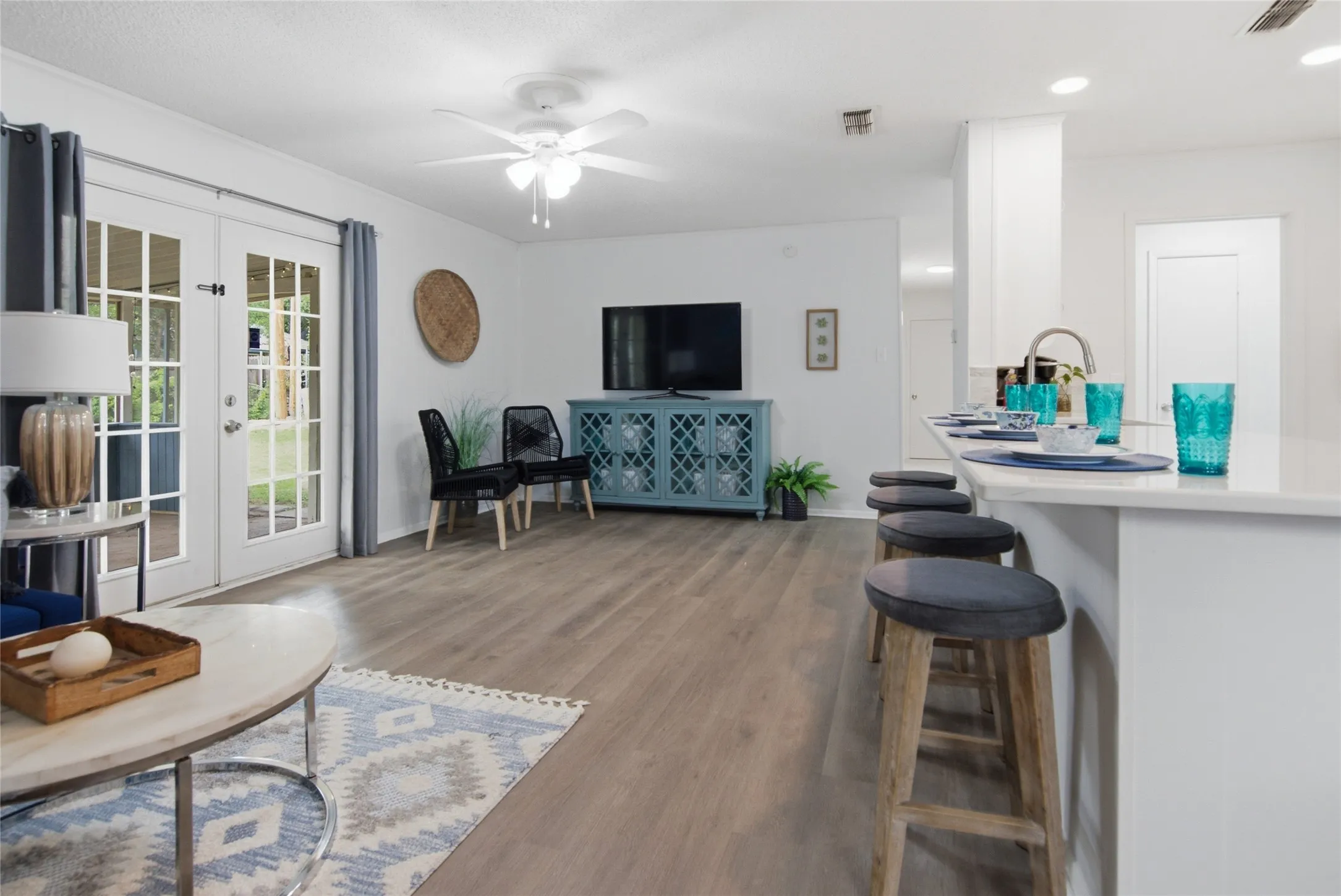 Open-concept living space featuring wood-finish flooring, white walls, and a ceiling fan