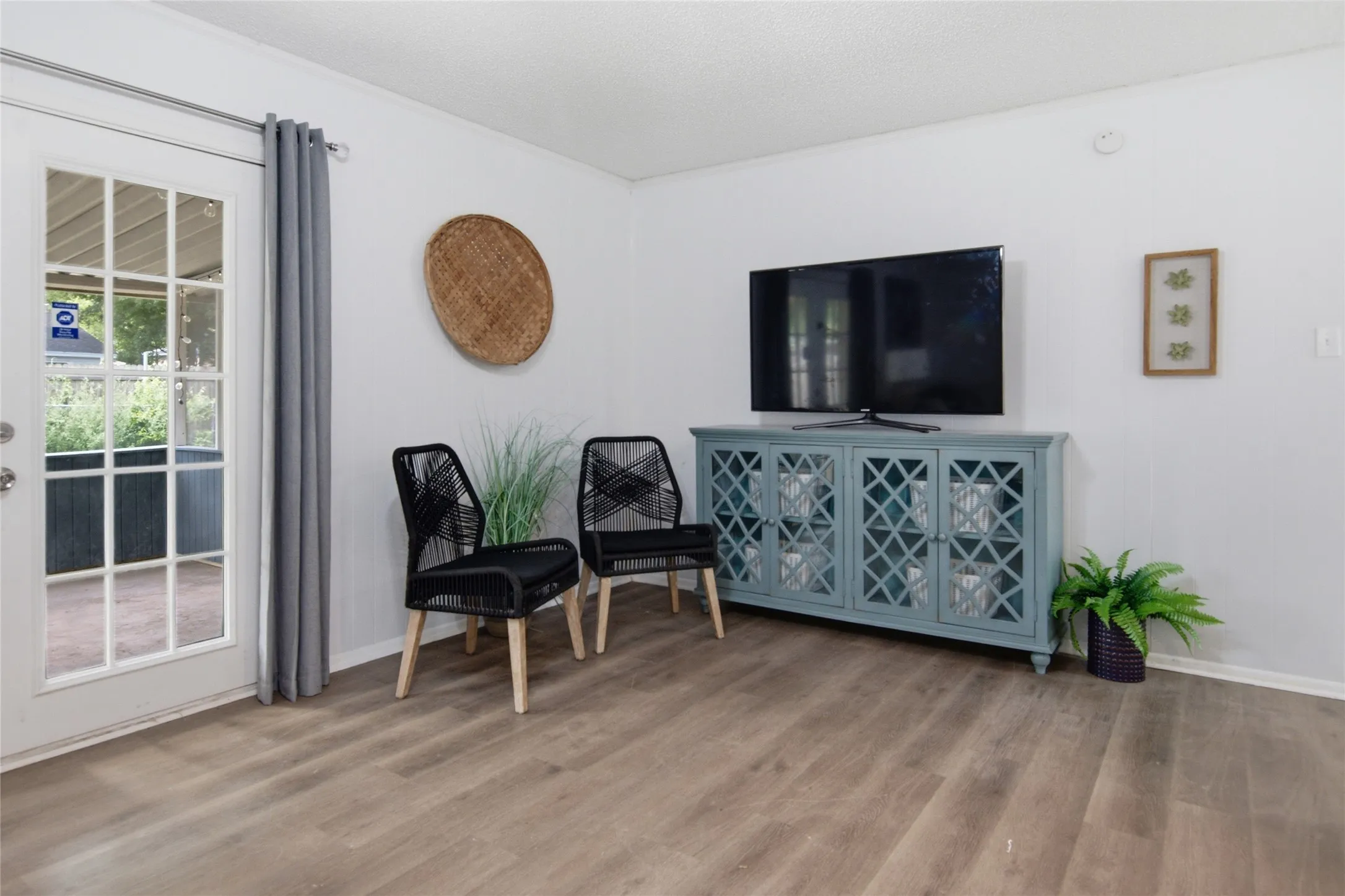 Interior space featuring wood-finish flooring, white walls, and a white French door leading to an outdoor patio