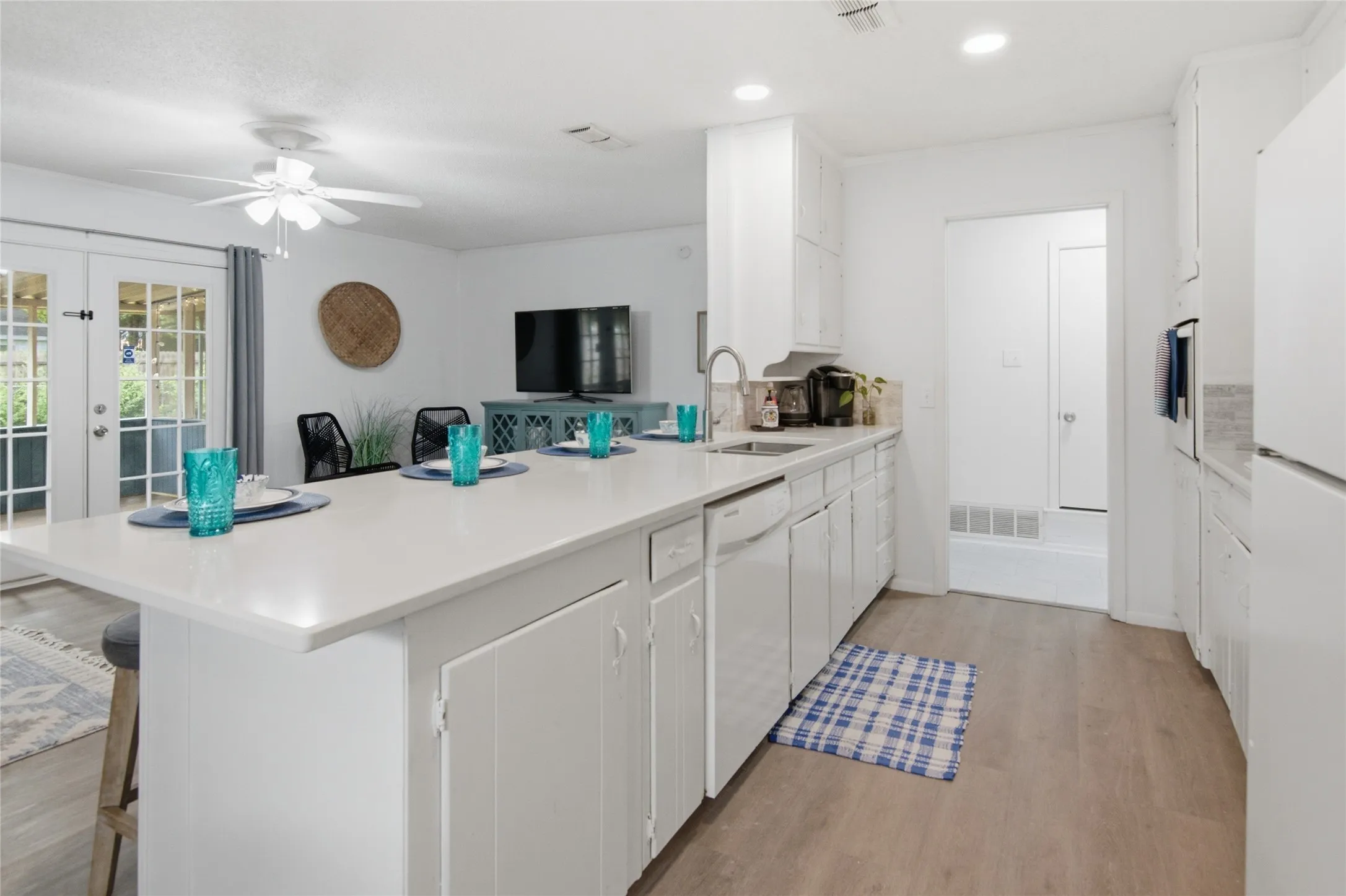 Kitchen featuring a large island with a light-toned countertop, white cabinetry, integrated sink, and stainless steel faucet