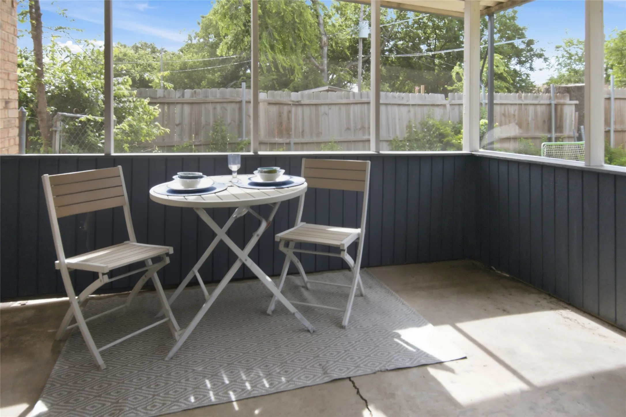 Screened porch with concrete flooring and dark vertical paneling