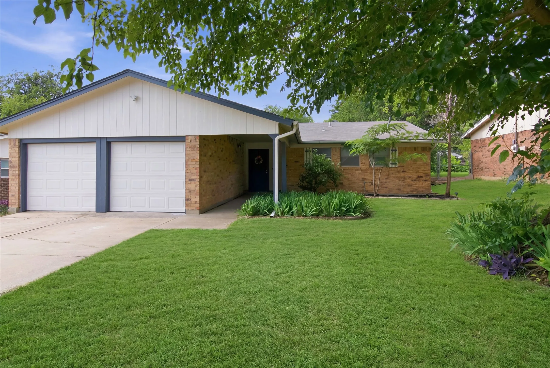 Brick exterior with white siding and a two-car garage