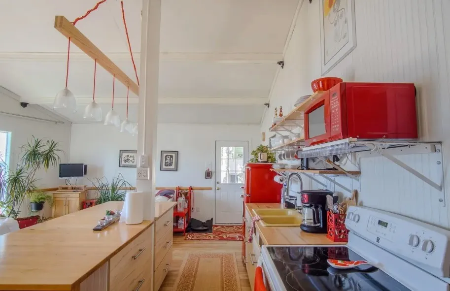 Bright kitchen featuring a white electric range, light wood-finish countertops, and beadboard paneling