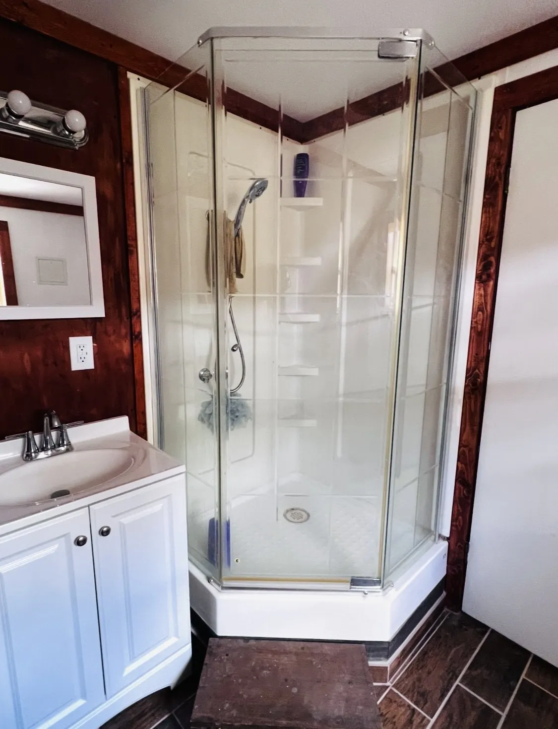 Corner shower enclosure featuring clear glass panels and interior shelving